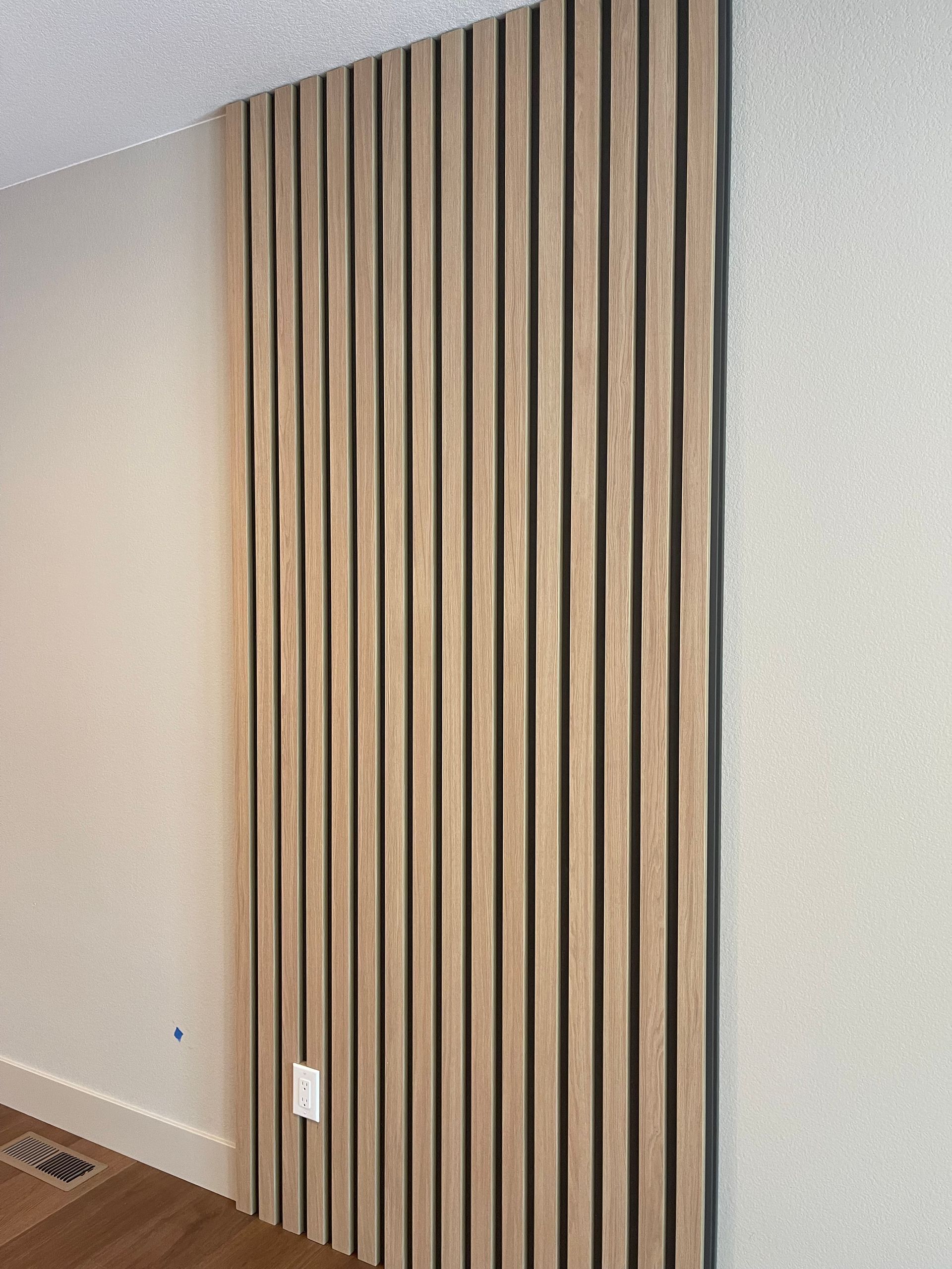 Wood-paneled accent wall with vertical slats in a bright, minimalist room