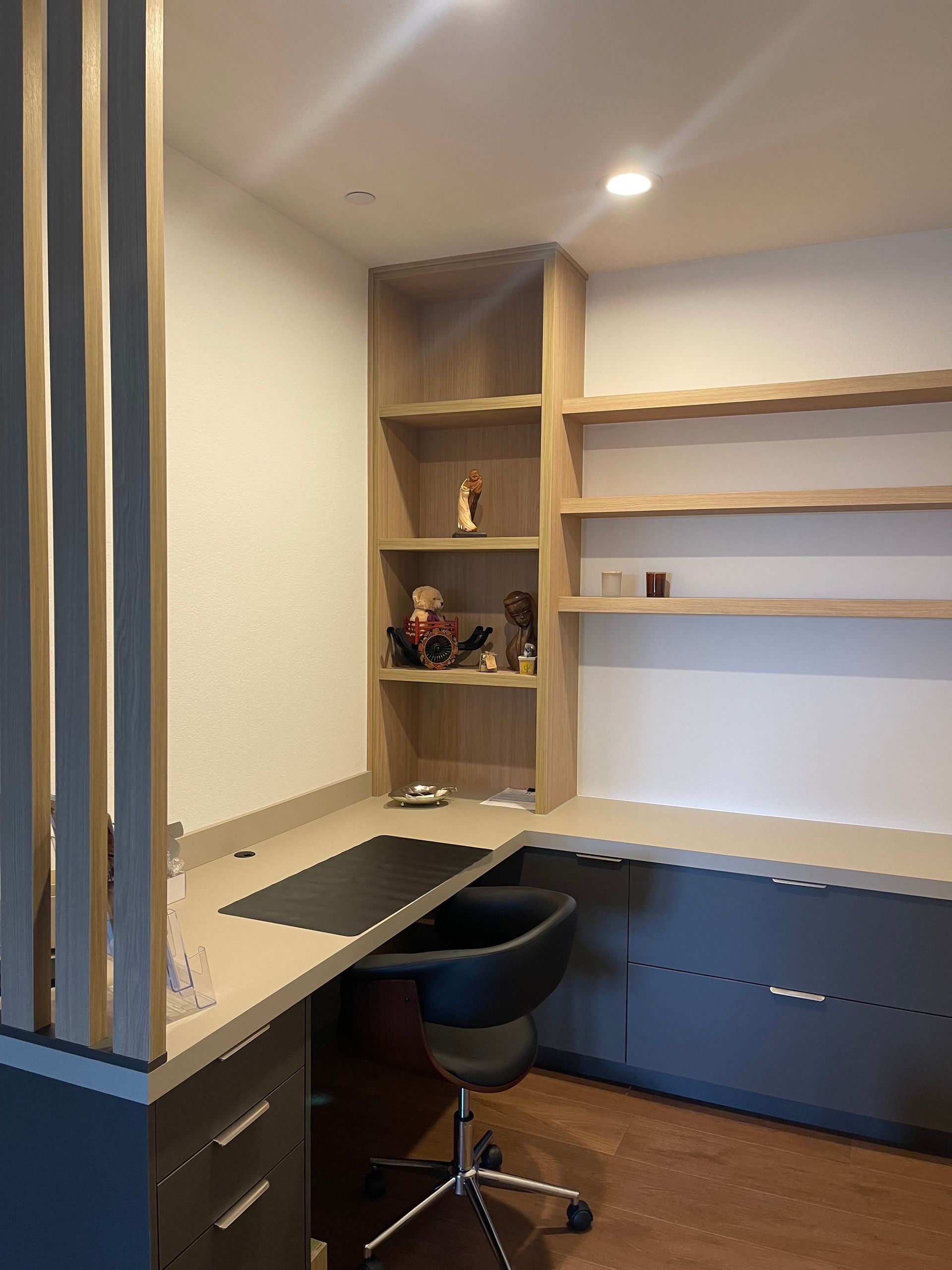 Built-in desk nook with shelves, black chair, and gray cabinetry in a modern room