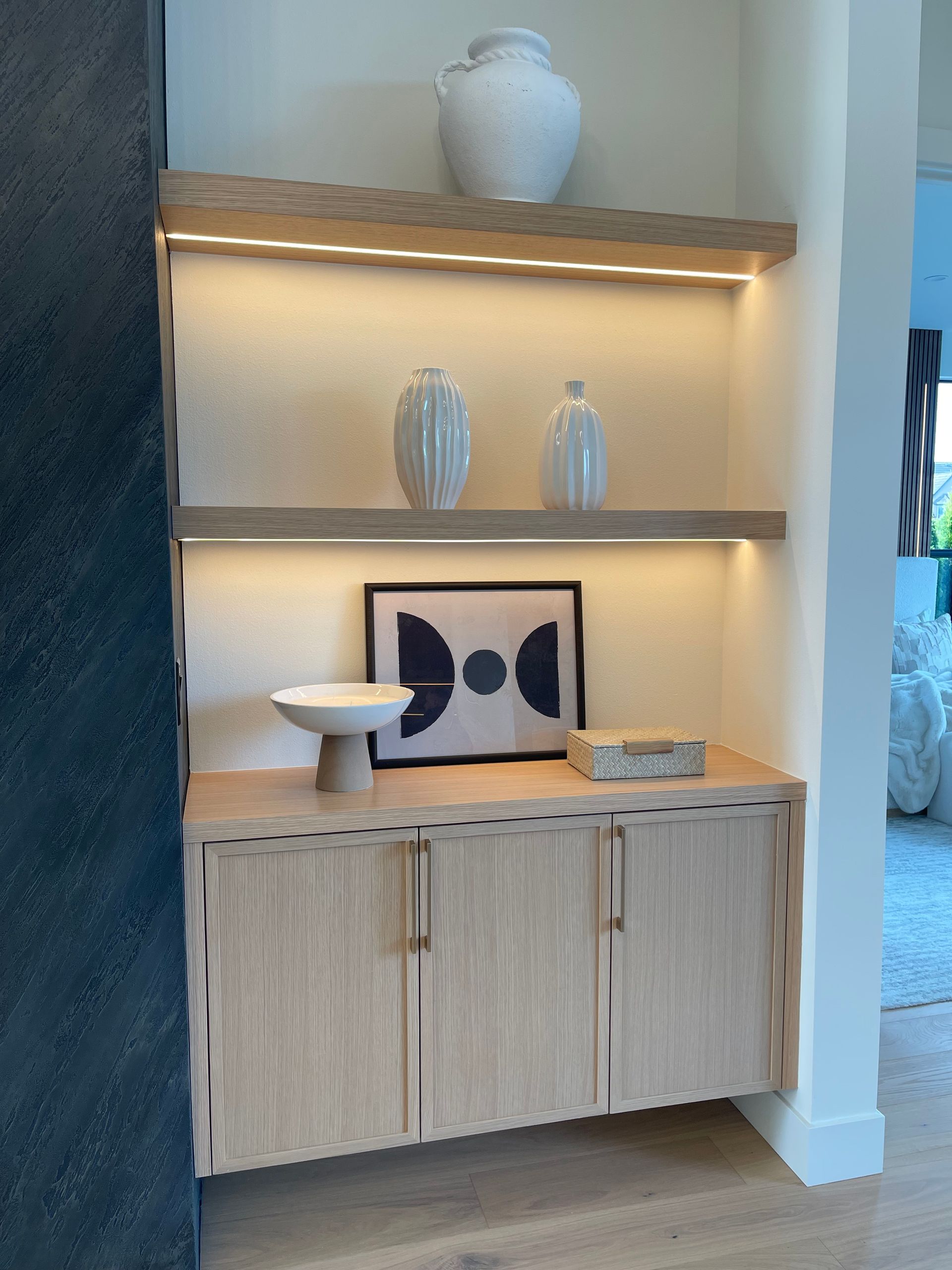 Built-in alcove shelf with vases, framed art, and a white bowl above wood cabinets in Portland, from Pro-techwoodworkig