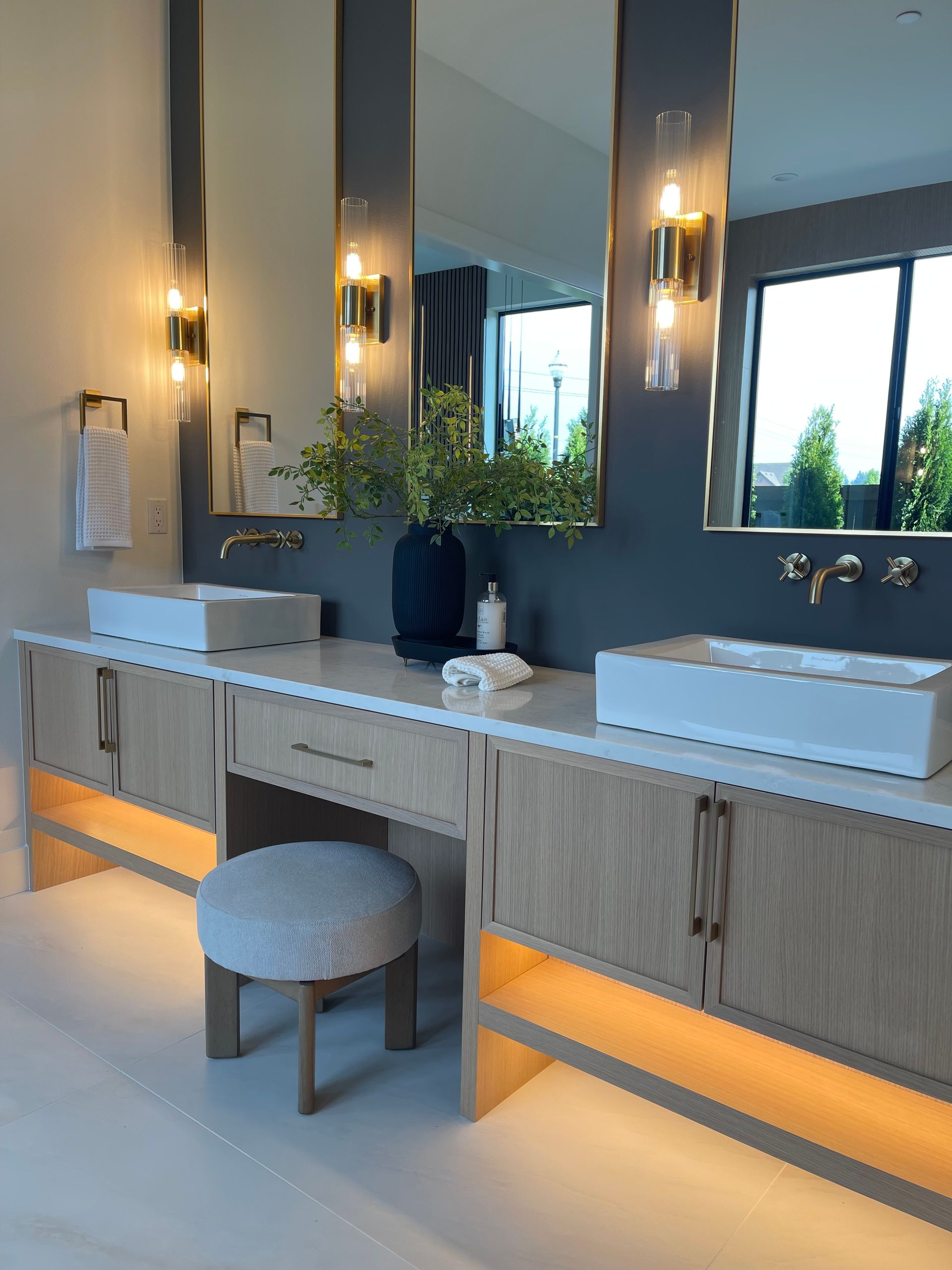 Modern bathroom vanity with double sinks, tall mirrors, pendant lights, and under-cabinet lighting