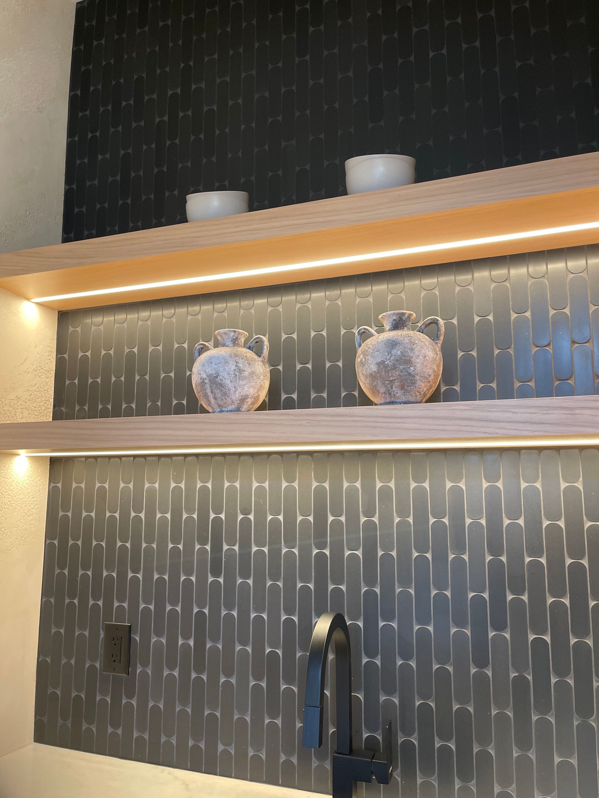 Backlit wall shelves with two decorative ceramic jars against dark patterned wallpaper