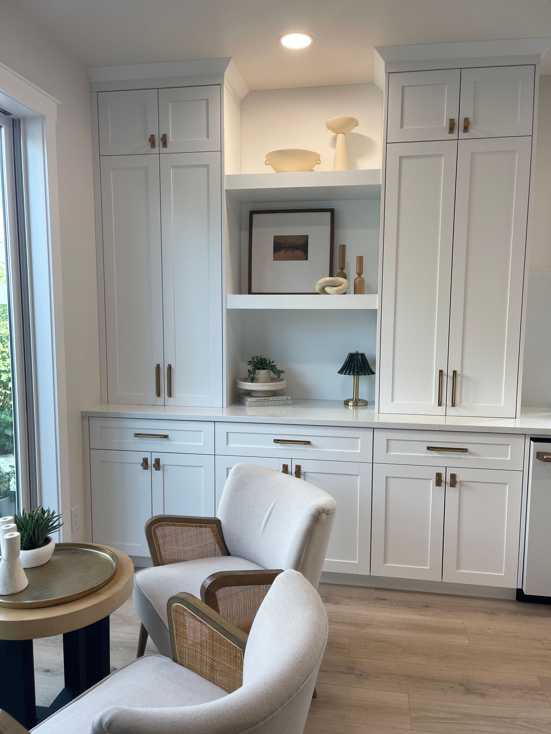Bright built-in white cabinets and shelves in a cozy living room with wicker chairs and wood floors