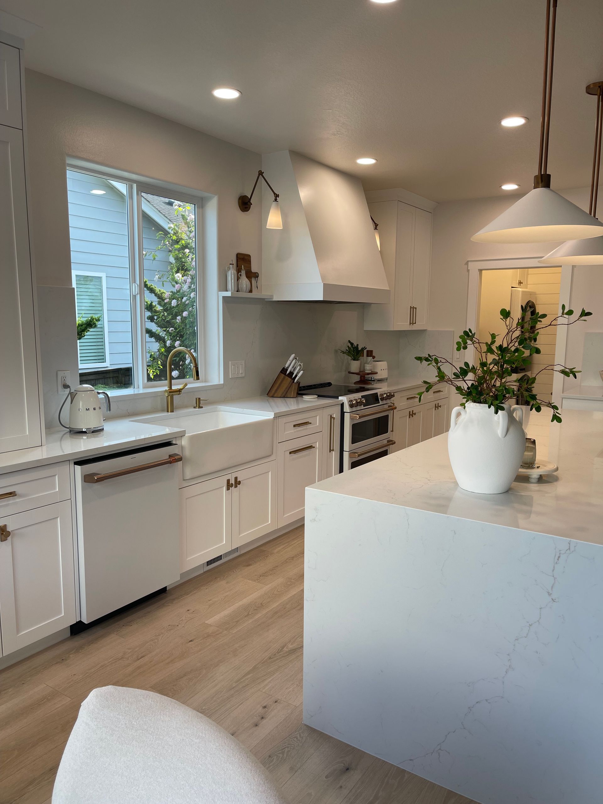 Bright white kitchen with island, pendant lights, and large window over the sink