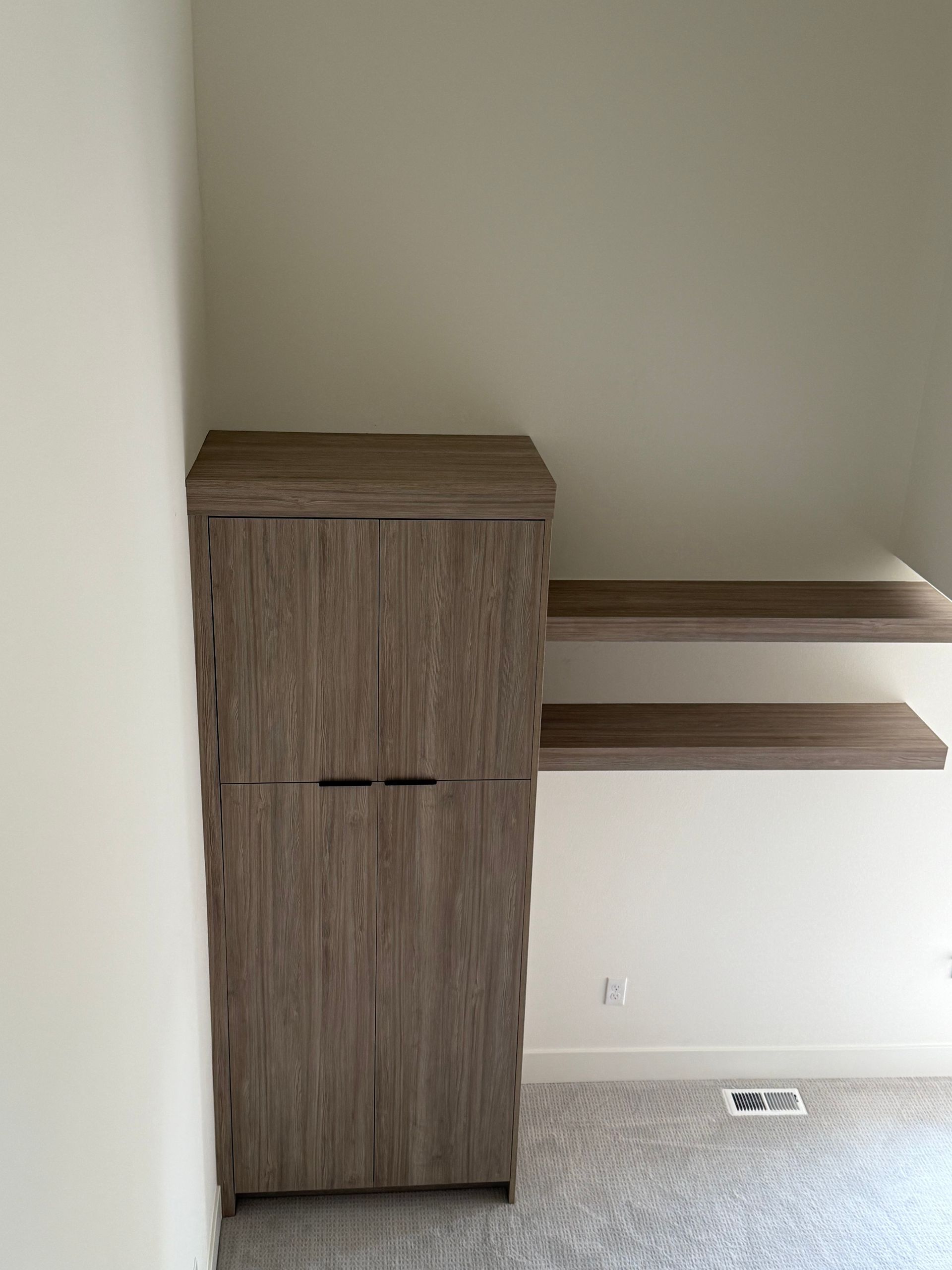 Wooden cabinet and two shelves built into a wall corner.