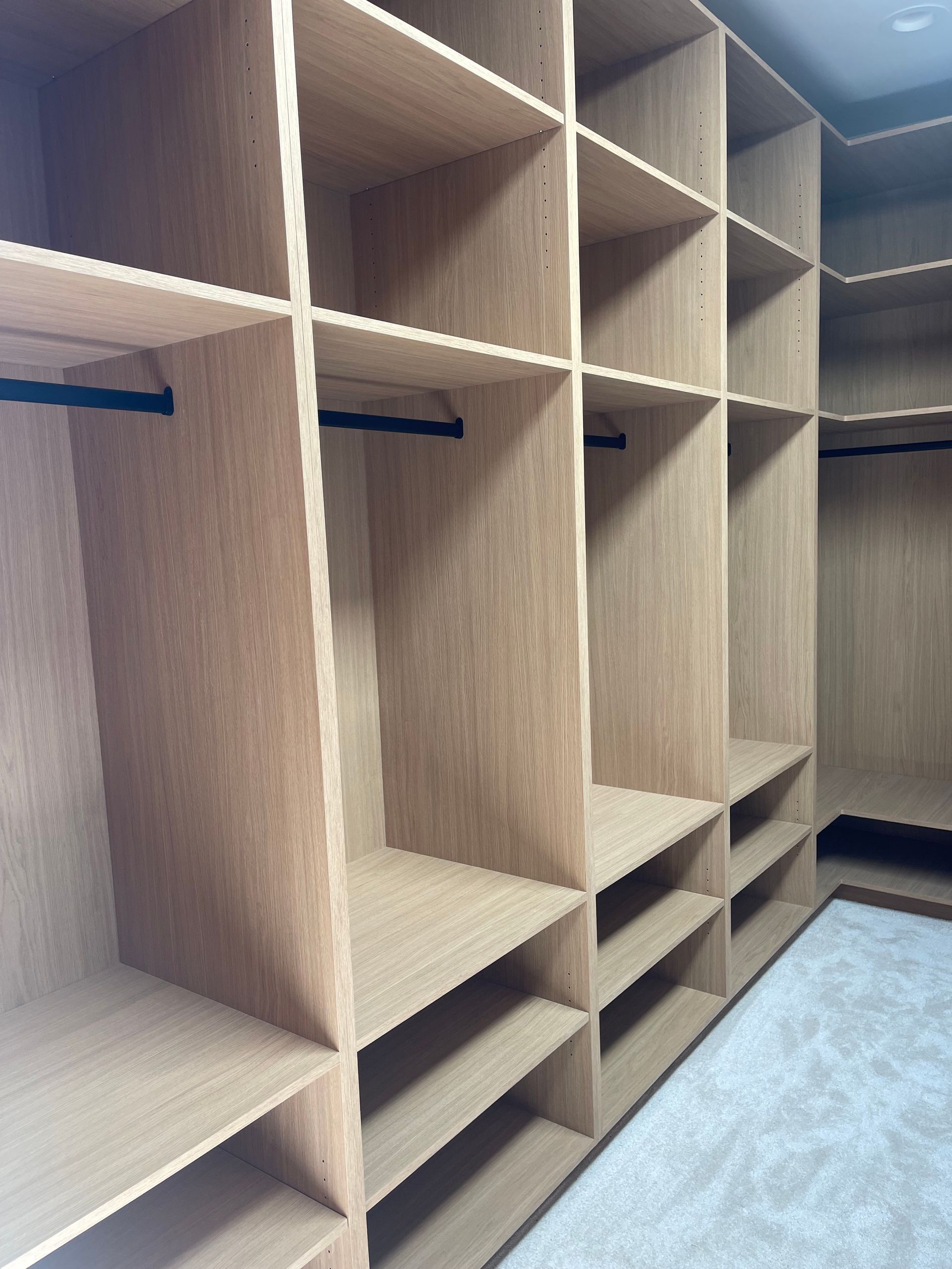 Wooden custom closet with shelves and hanging rods.