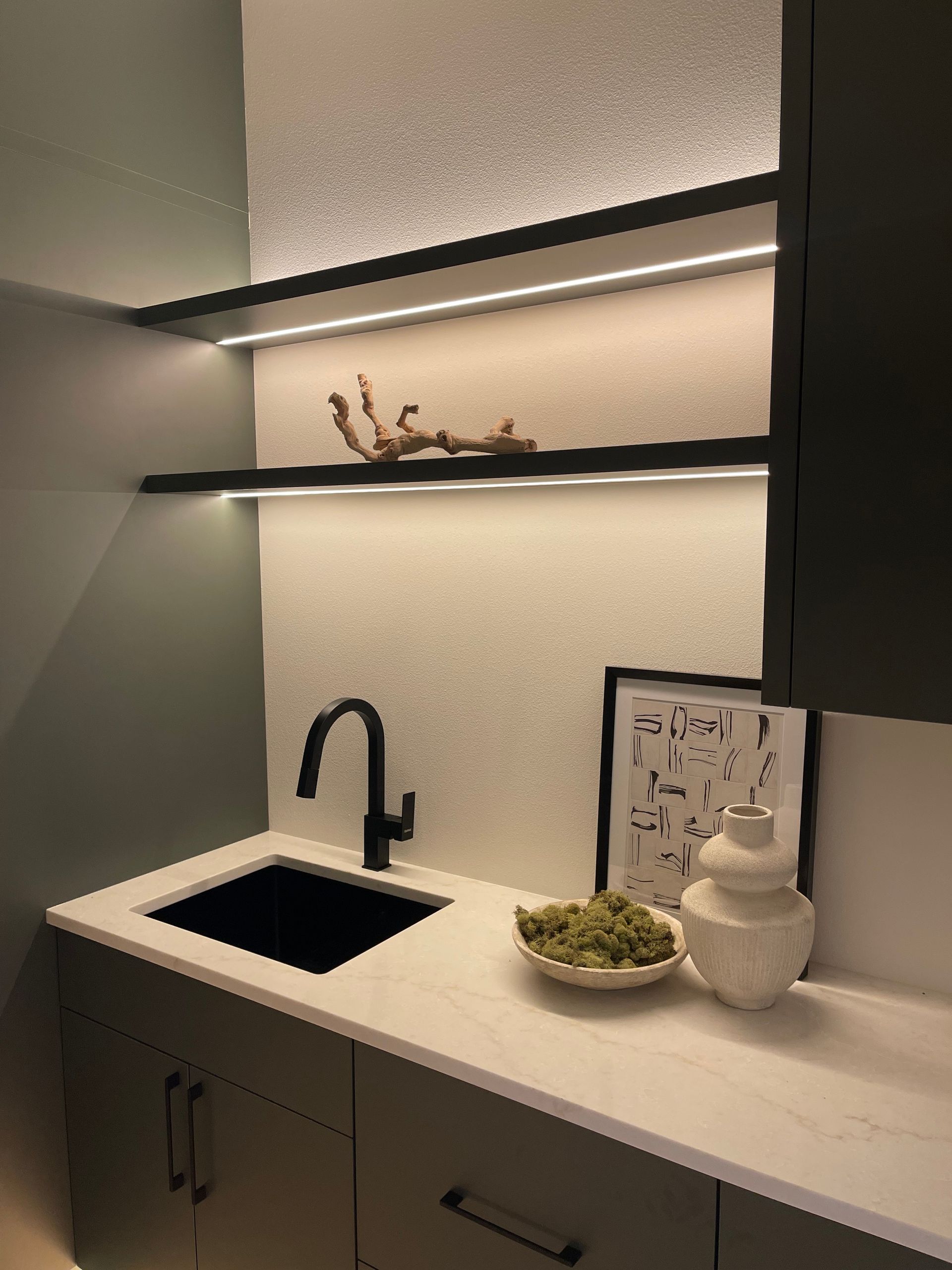 Modern kitchenette with black sink, floating shelves, white countertop, and a small plant in Portland, Oregon, WA