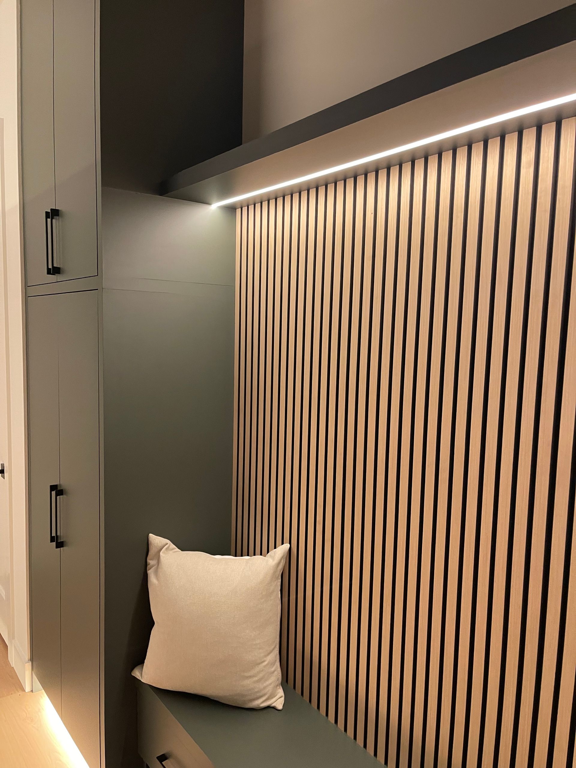 Modern interior with striped wood wall panel, under-cabinet lighting, and a white cushion on the floor in Portland, Oregon