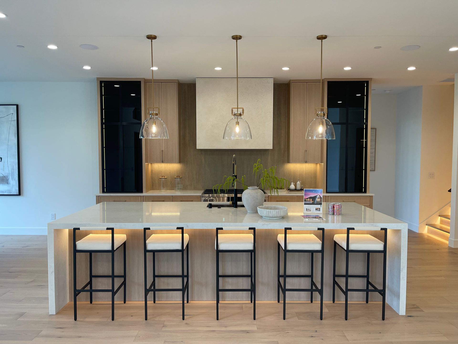 Modern kitchen with a large island, pendant lights, and five bar stools.
