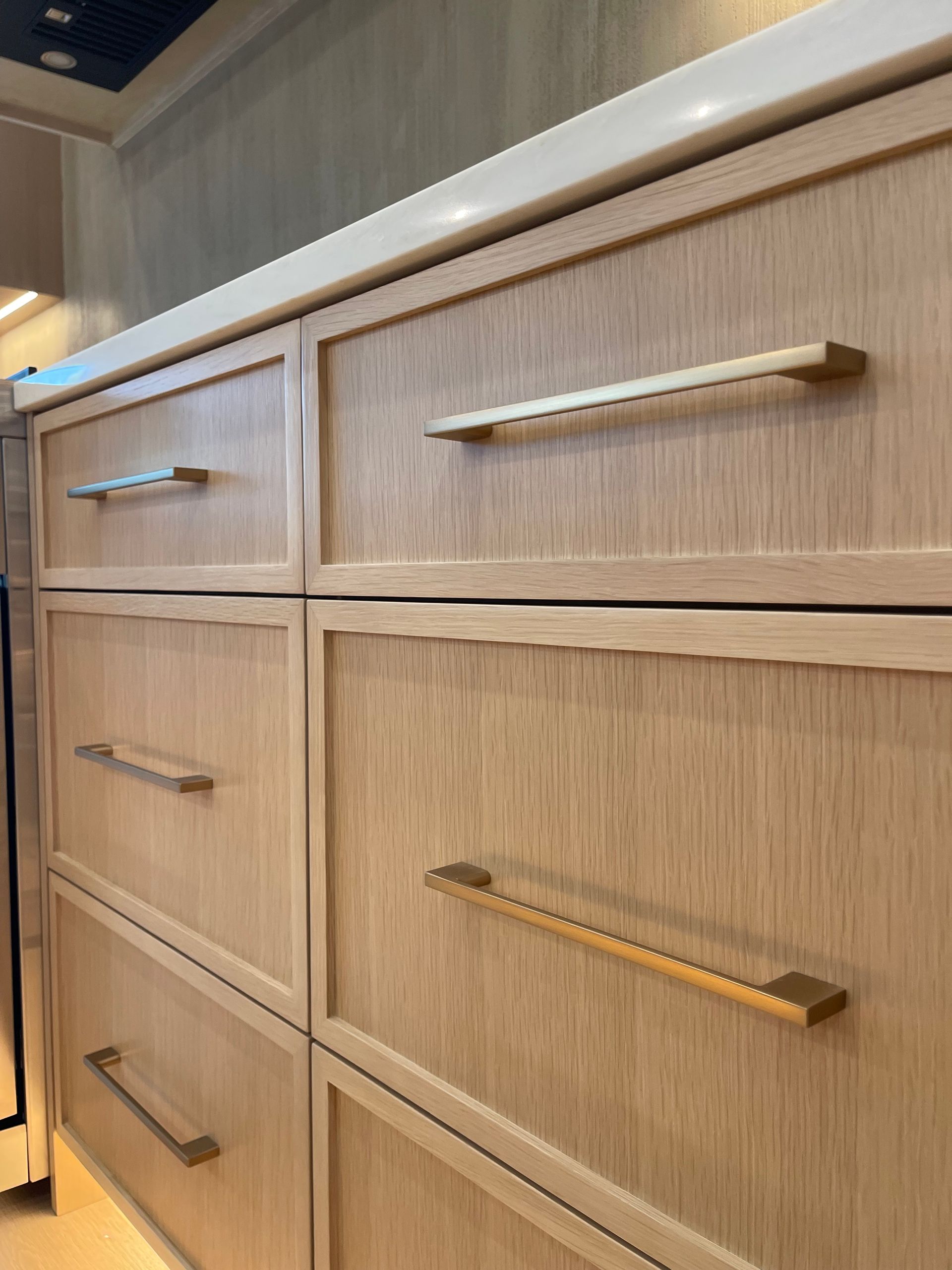 Wooden kitchen cabinet drawers with long silver handles, viewed at an angle