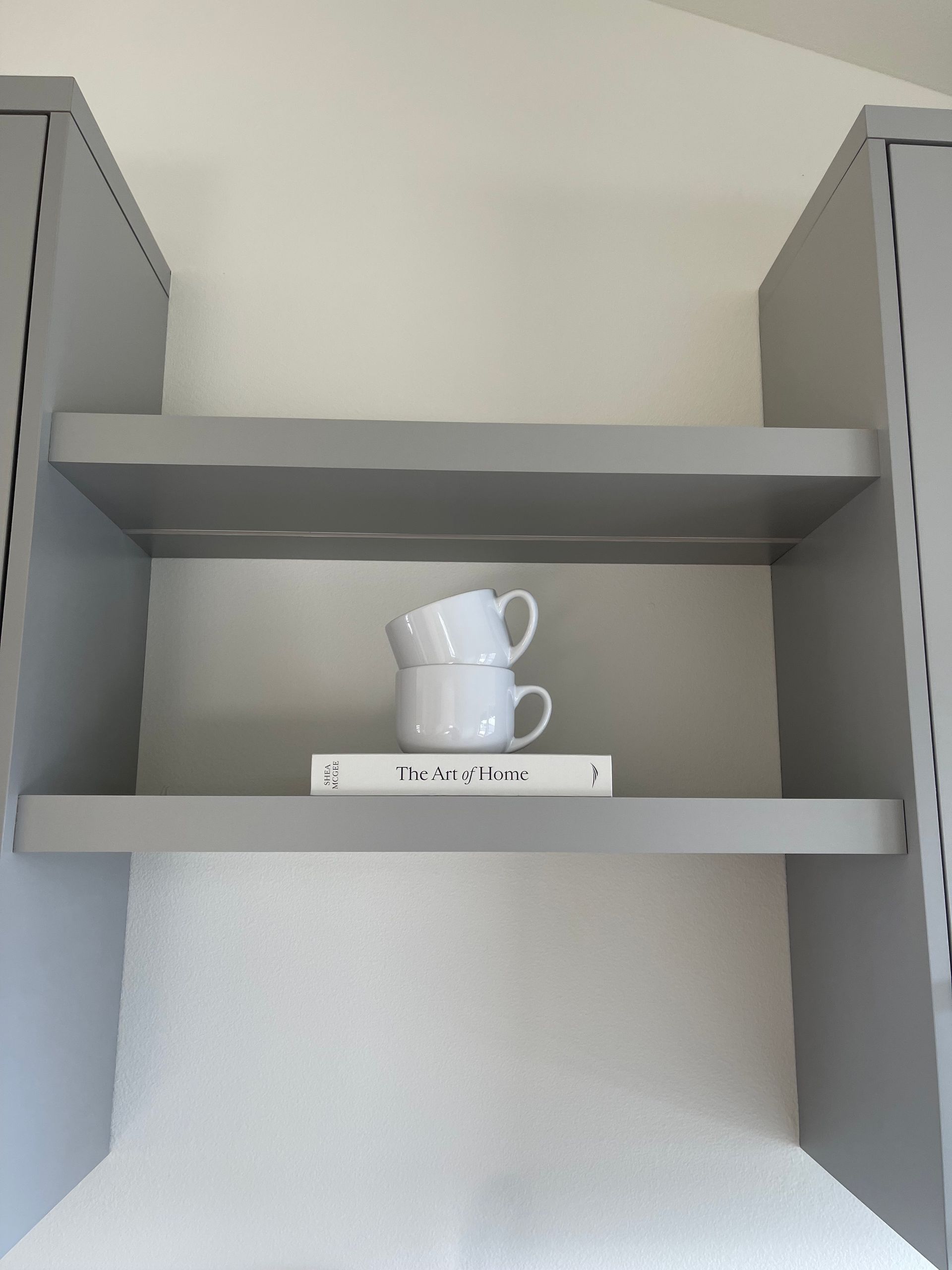 White teacups stacked on a gray shelf between two cabinets in Portland, Oregon, WA