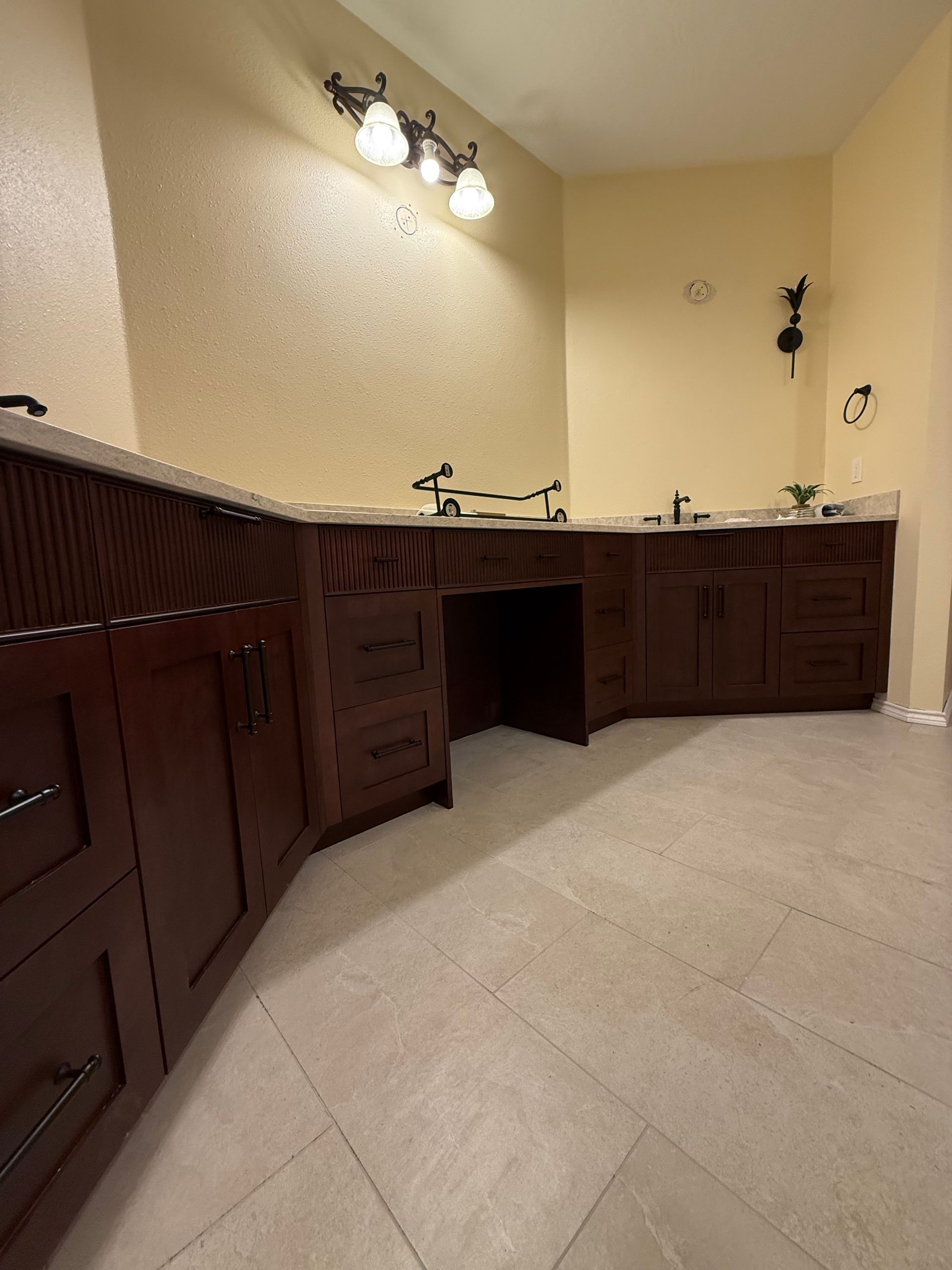 Dark wood bathroom cabinets with light countertops and beige walls.