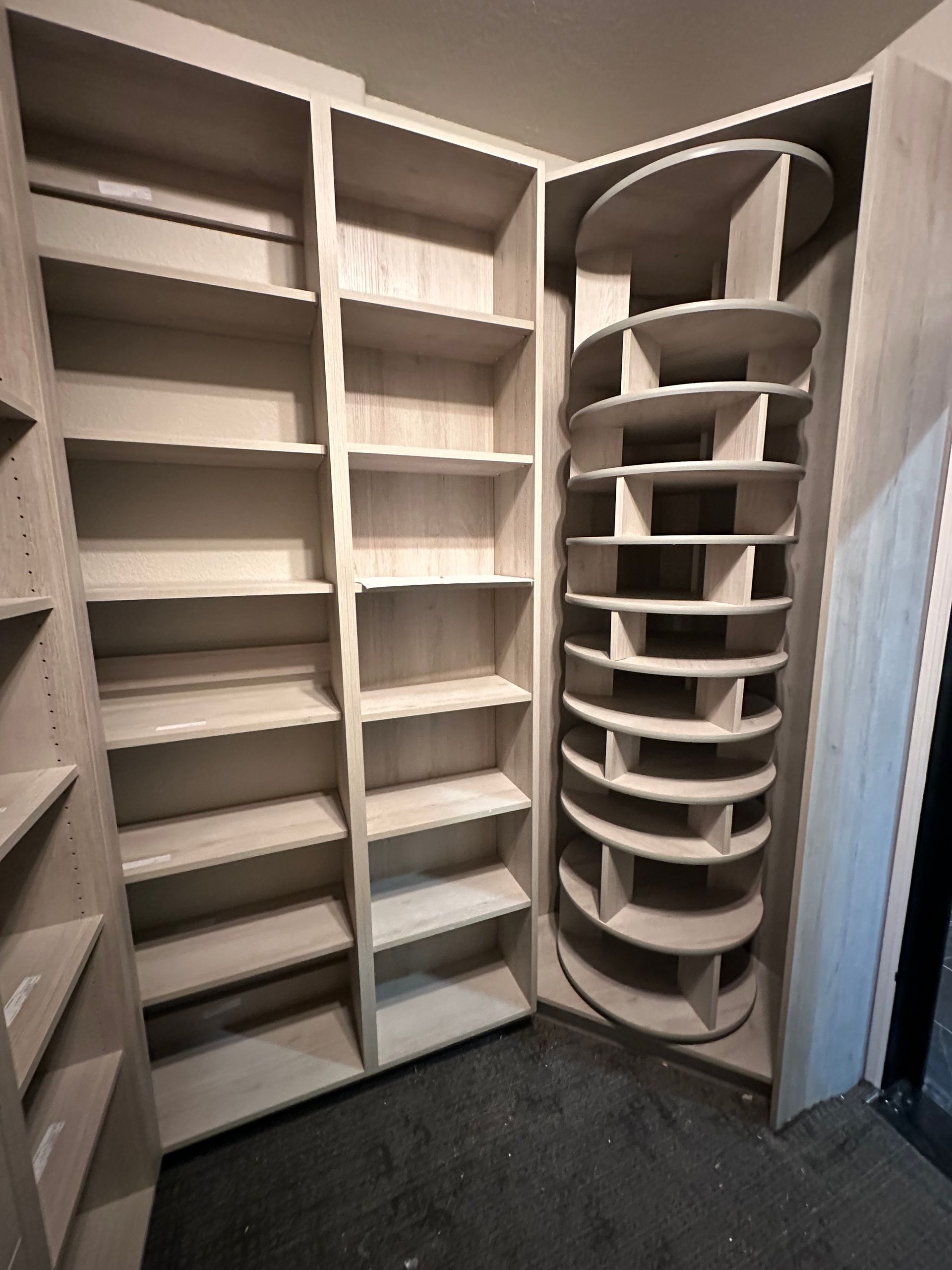 Corner closet with built-in shelves and a rotating circular shelf unit; light wood.