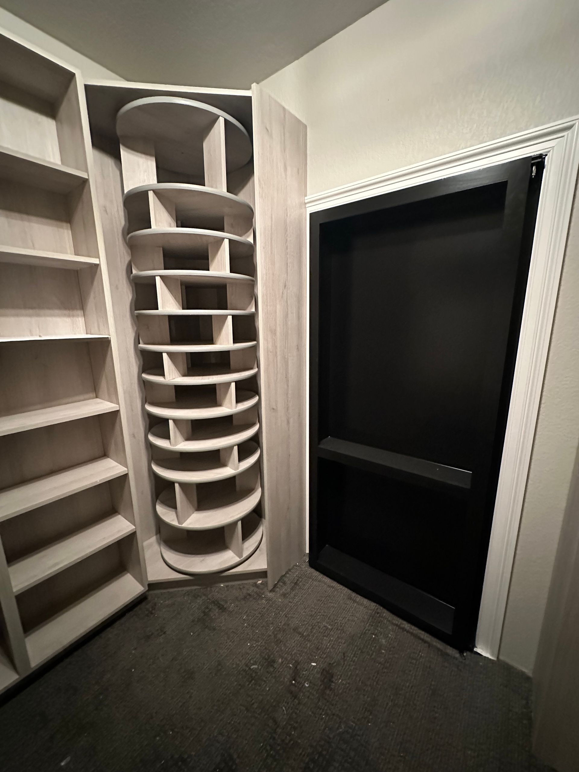 Corner closet with shelving, including a spiral shoe rack and a black recessed storage area.