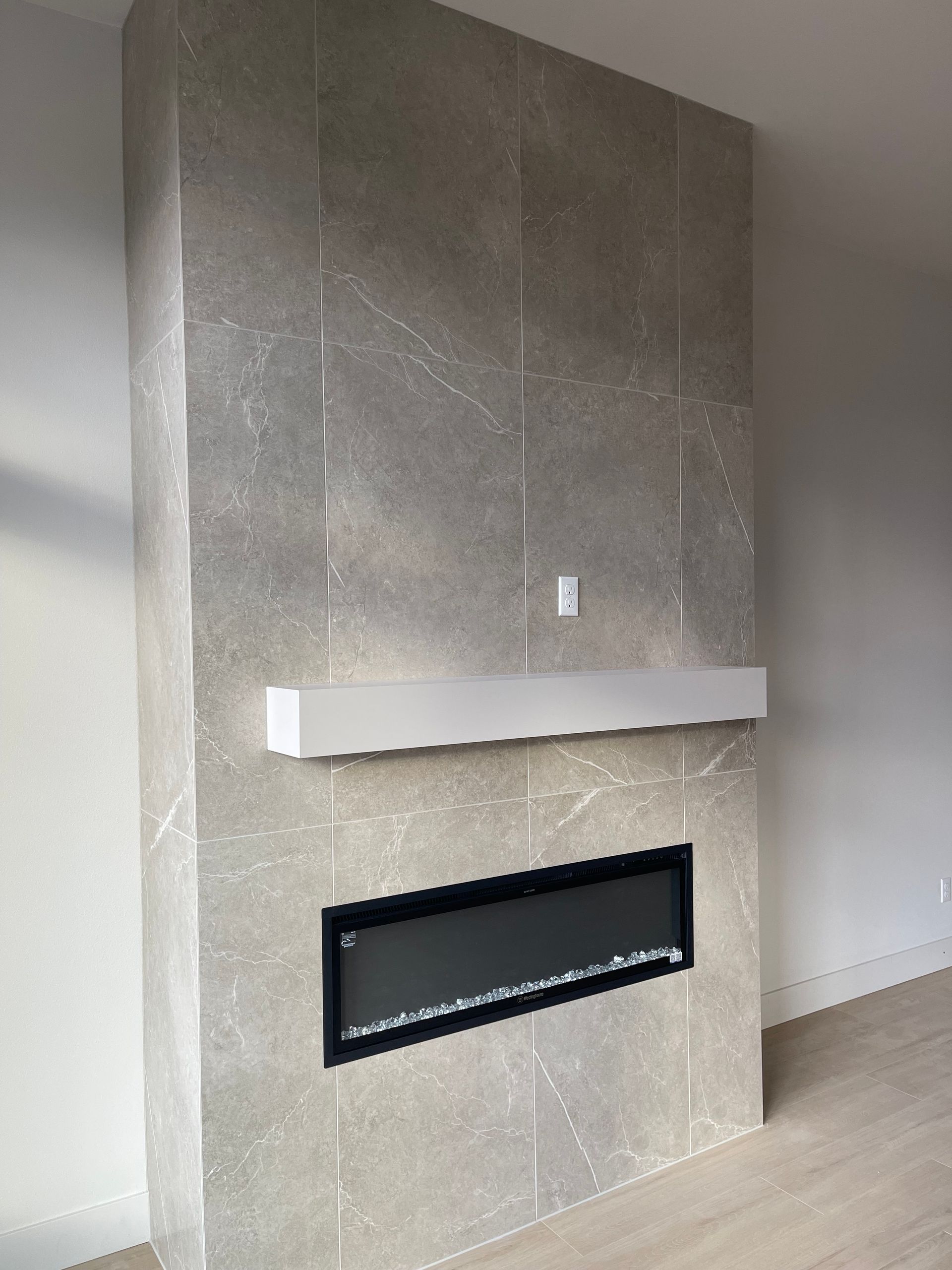 Gray tiled fireplace with white mantle and black framed insert.