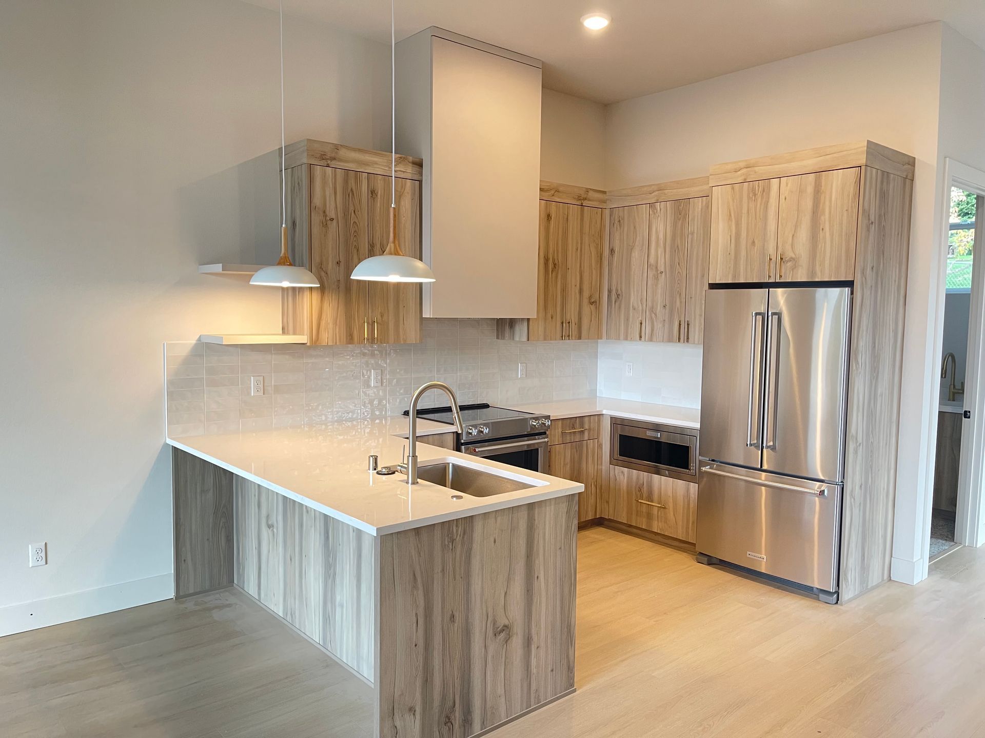 Modern kitchen with wood cabinets, stainless steel appliances, and white countertops.