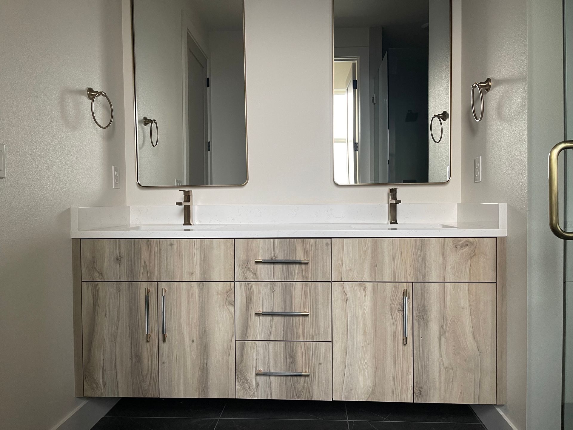 Bathroom with wood-look vanity, dual sinks, mirrors, and fixtures.