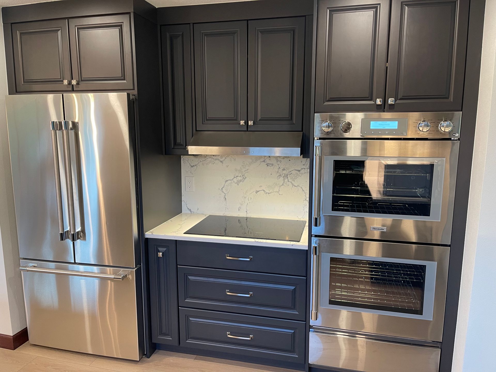 Stainless steel appliances and dark gray cabinets in a kitchen.