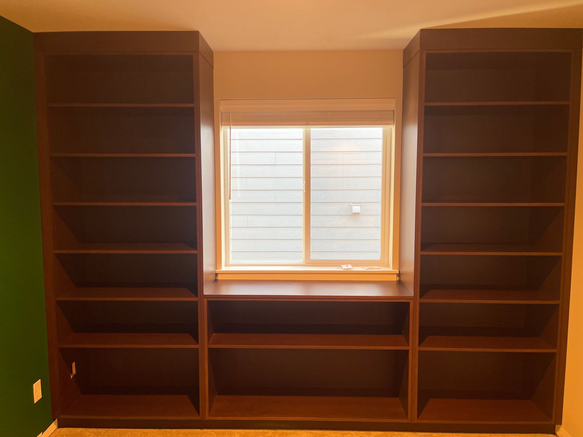 Built-in dark wood bookshelves framing a window in an empty room