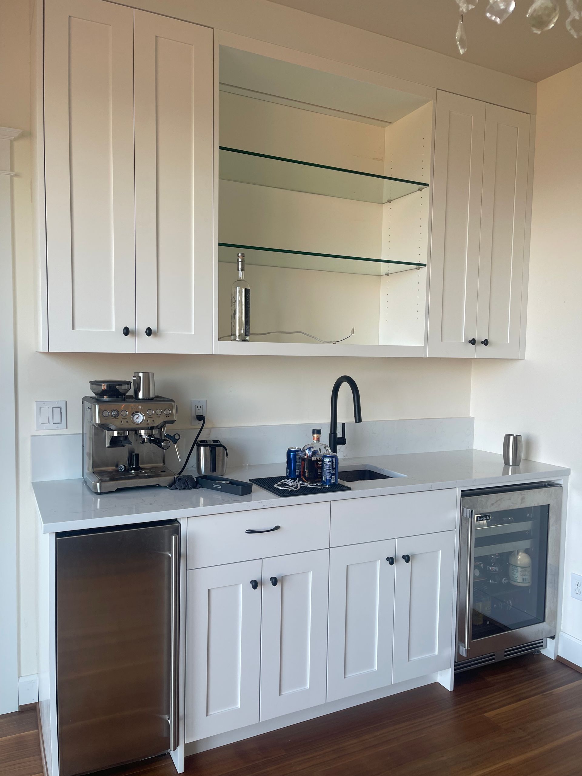 White kitchen bar with cabinets, a sink, and appliances.