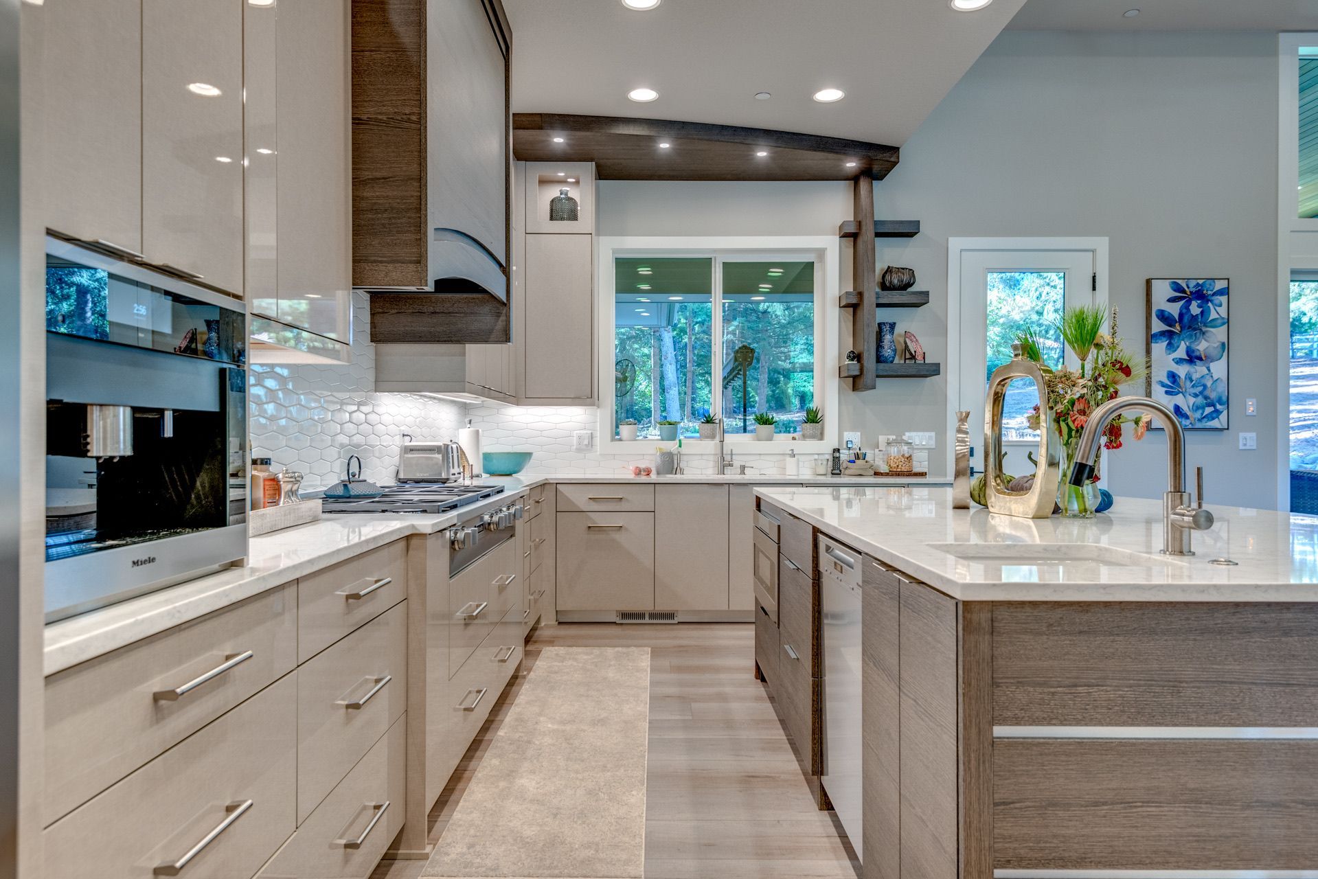 Modern kitchen with light cabinets, island, stainless steel appliances, and a view to the outside.