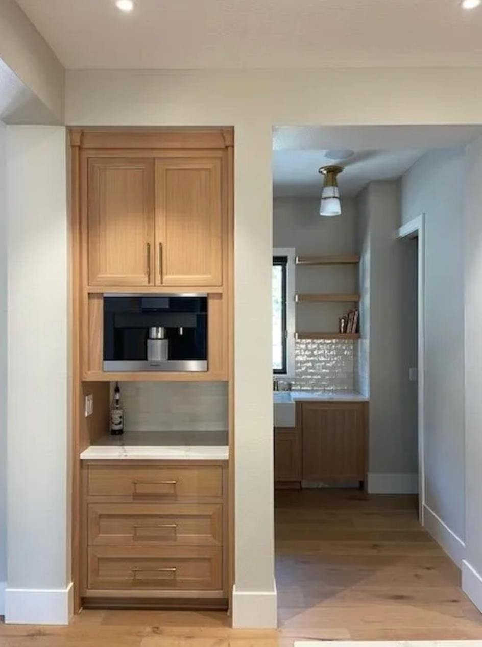 Coffee station with tall cabinet, wall oven, and wood grain finish in Happy Valley
