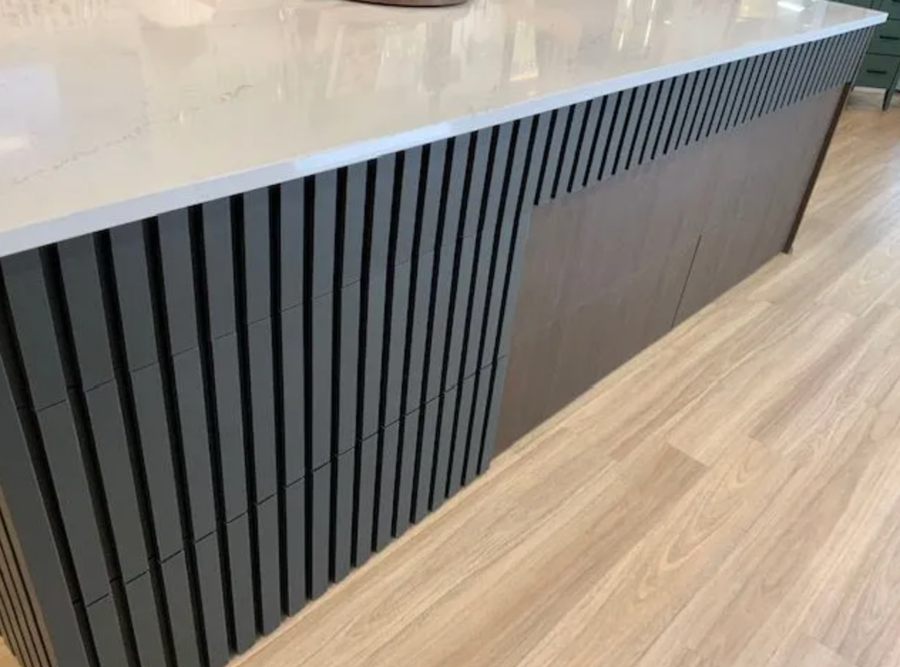 Gray kitchen island with vertical wood slat detailing and a light-colored countertop.