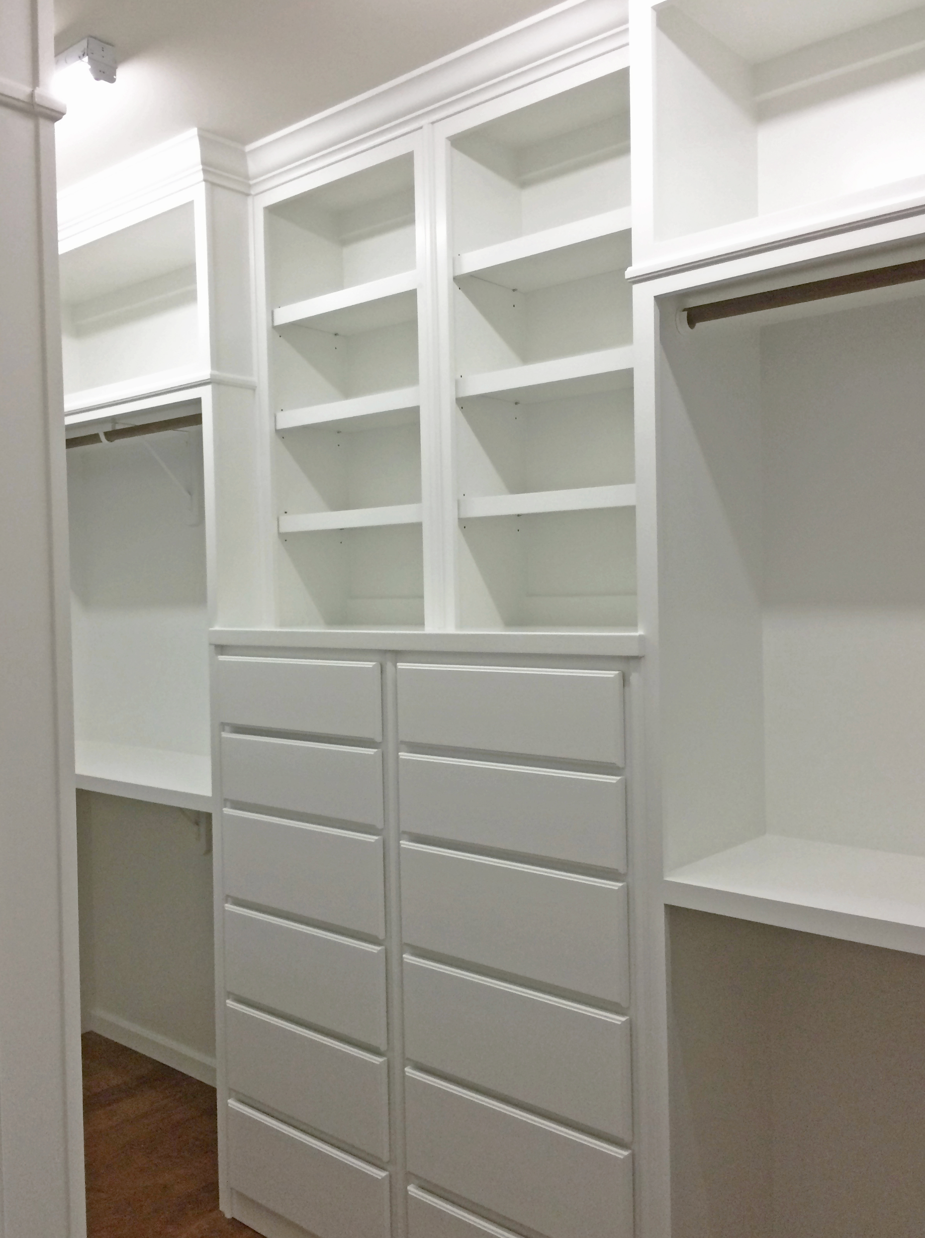 White closet with shelves, drawers, and hanging rods.