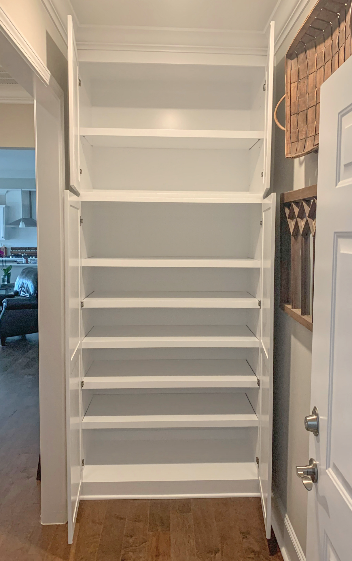 White, built-in shoe storage unit with multiple shelves. Doors are open, revealing empty shelves against a white wall.
