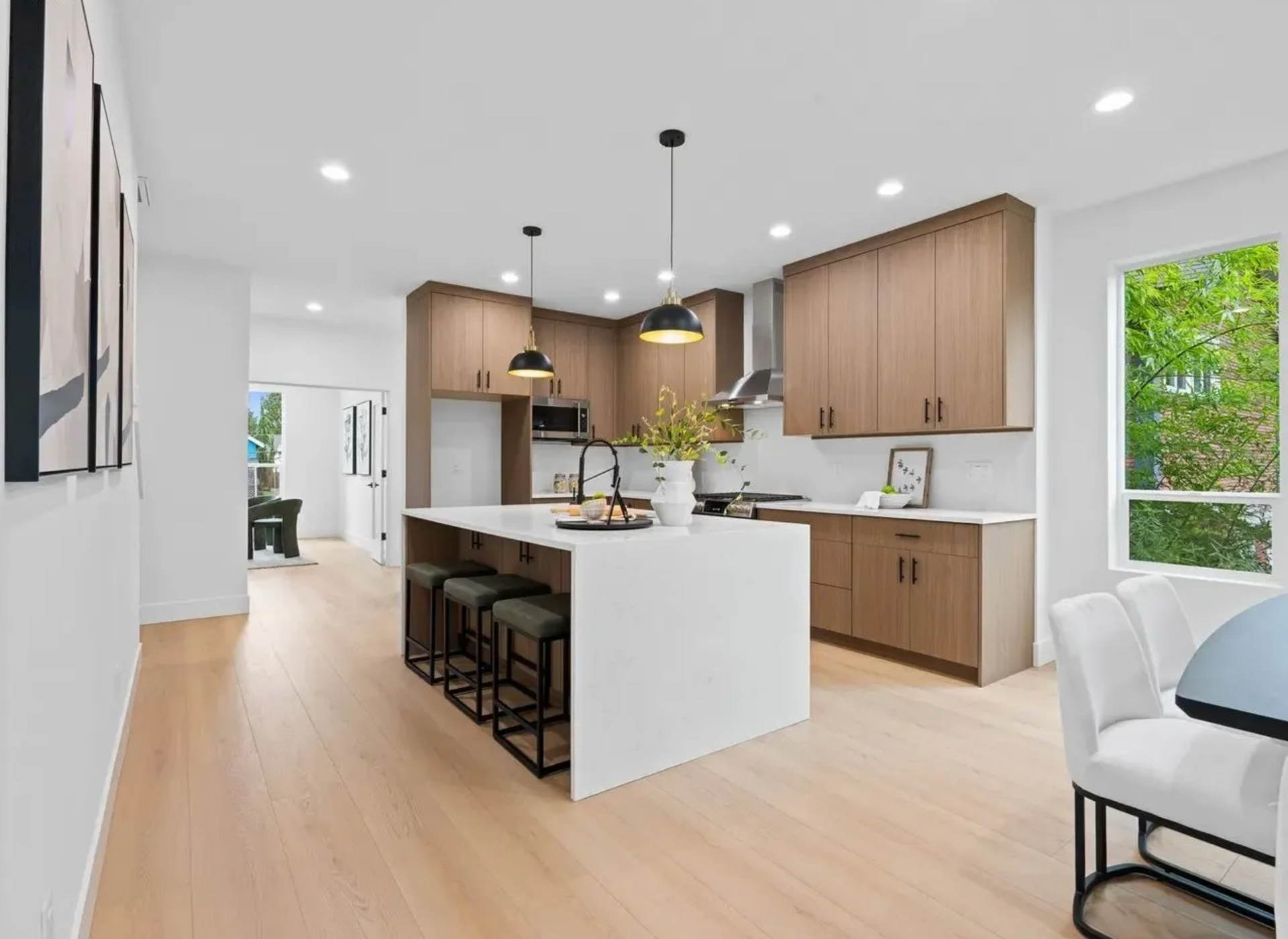 Modern kitchen with wooden cabinets, white island, and light wood flooring.