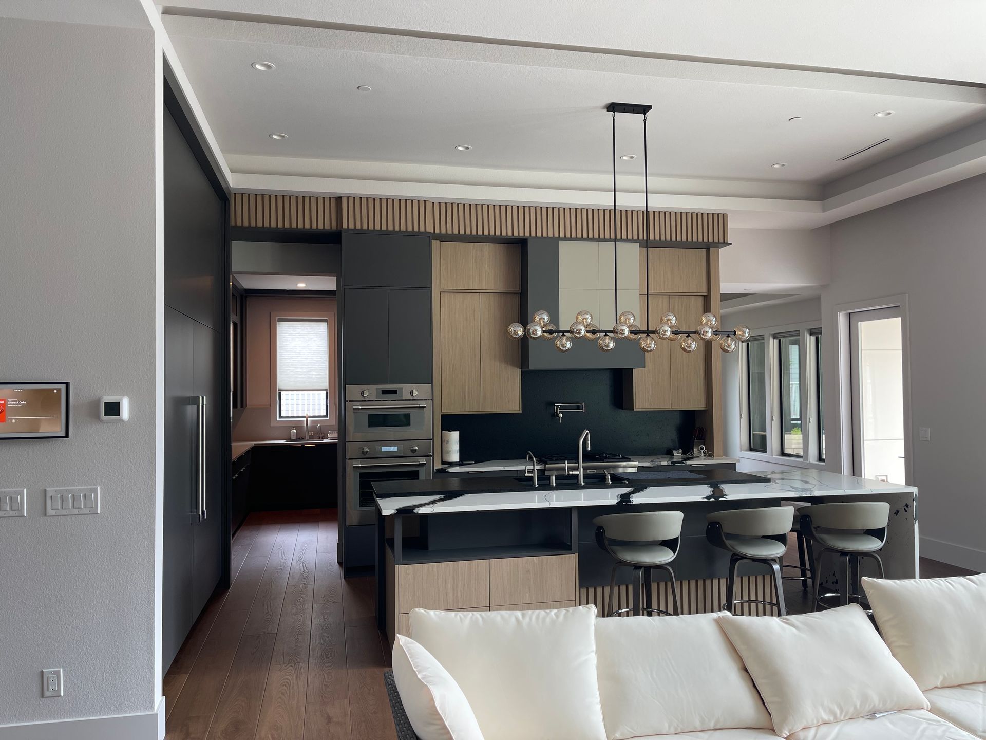 Modern kitchen with island, cabinets, and seating, connected to living area.