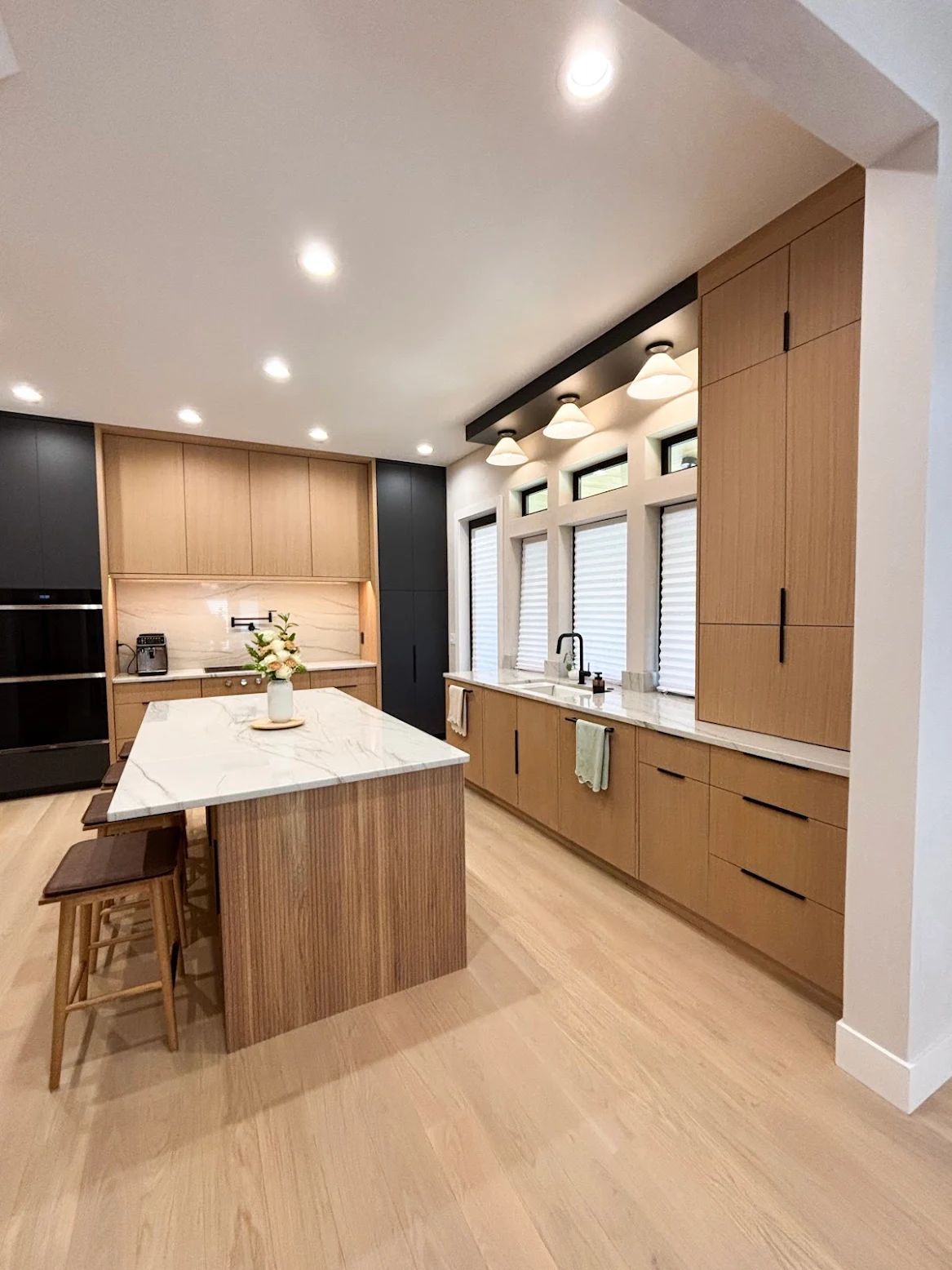 Modern kitchen with light wood cabinets, white countertops, and a large island.