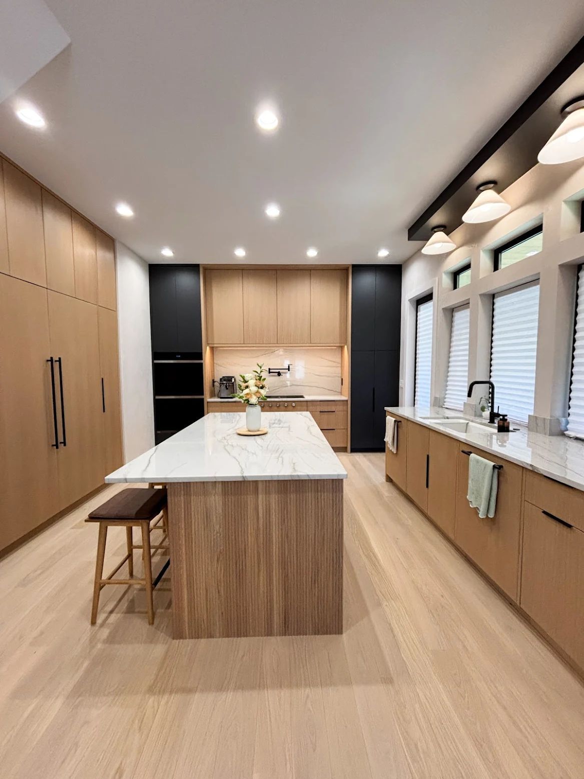Modern kitchen with wood cabinets, white countertops, and a large island.