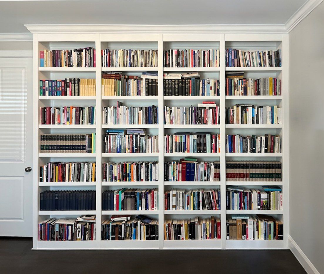 White bookshelf filled with books against a gray wall.