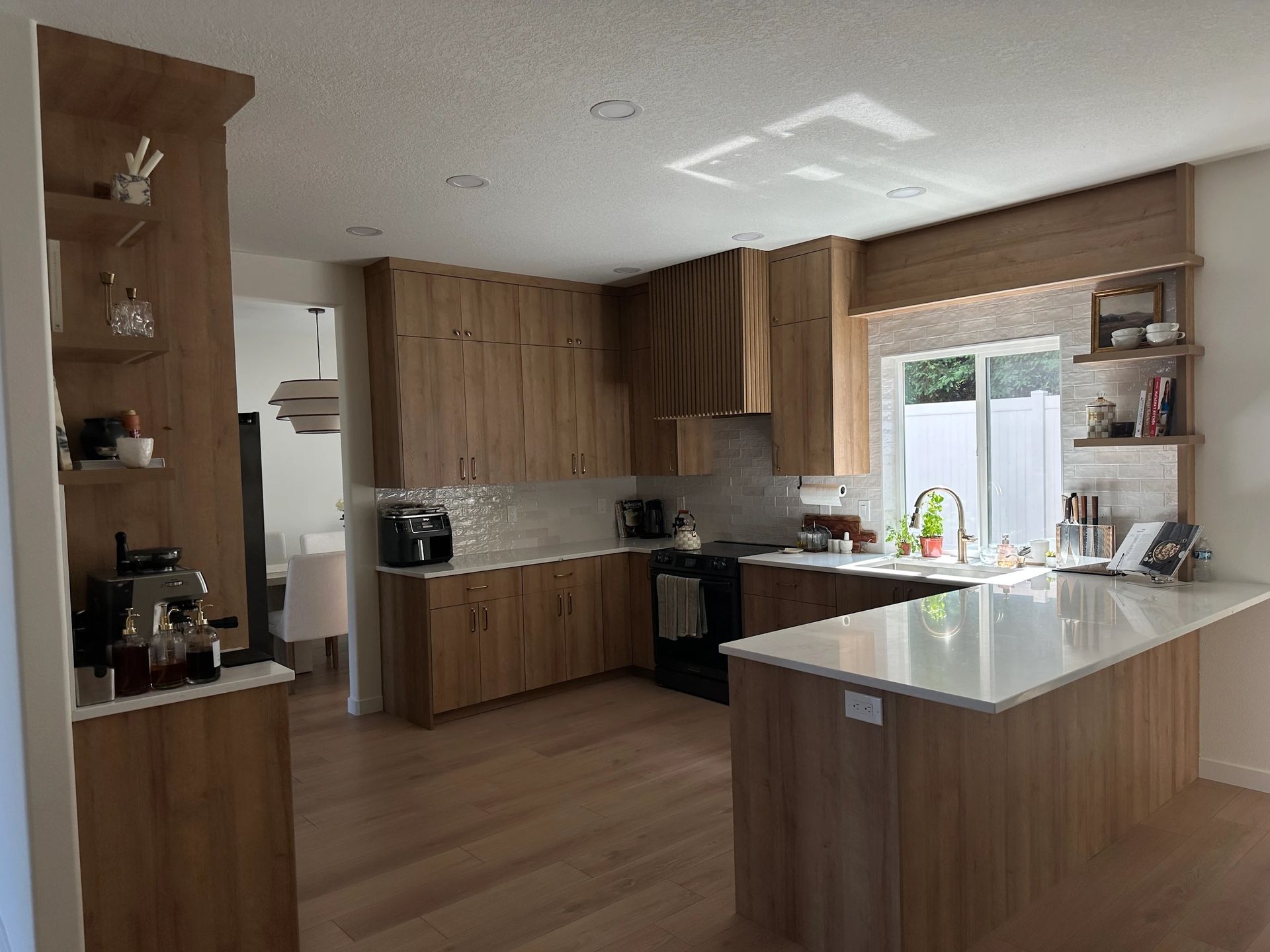 Modern kitchen with wooden cabinets, white countertops, and a kitchen island.