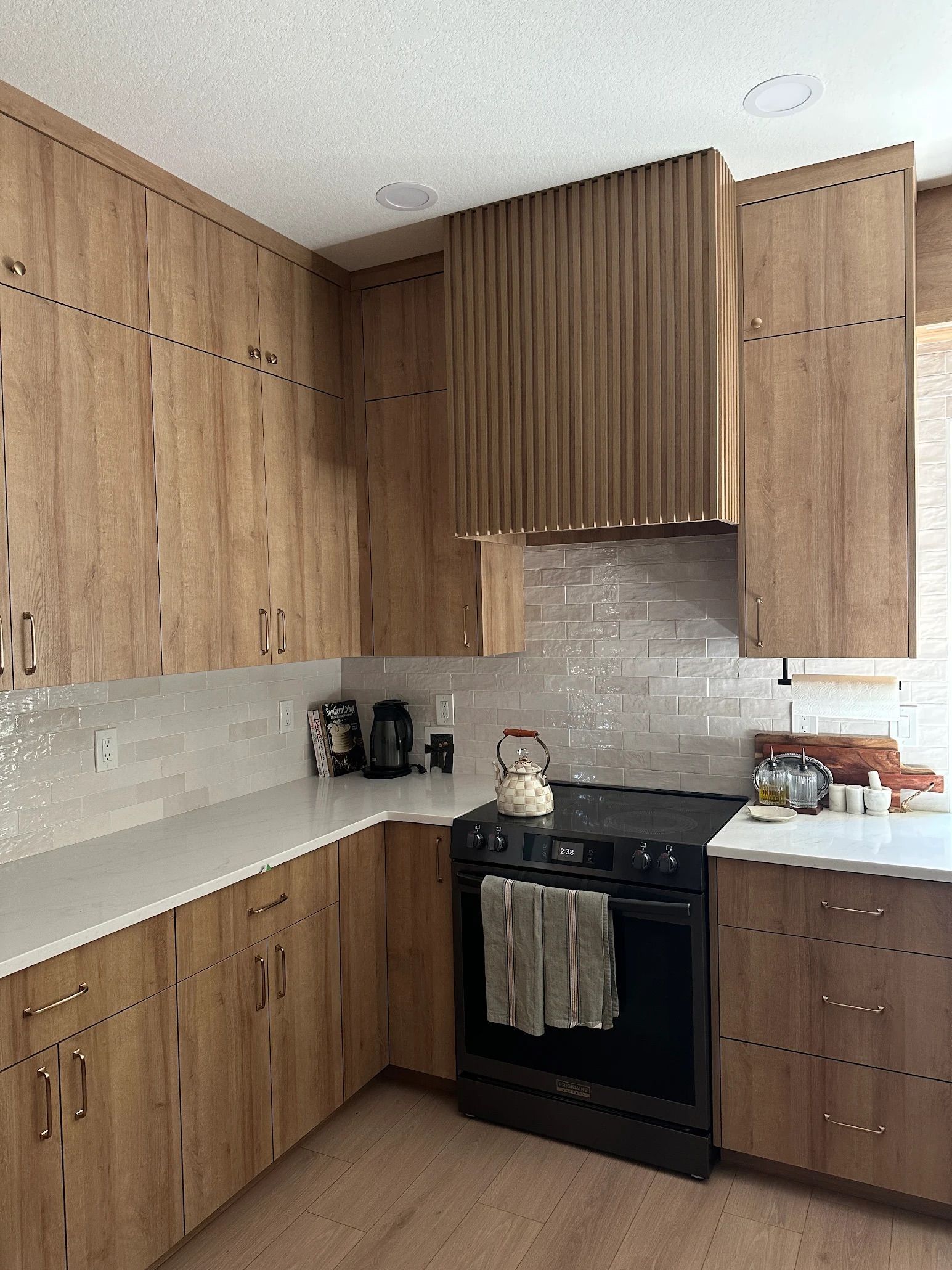 Kitchen with wooden cabinets, white countertops, and a black stove.