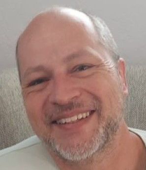 A bald man with a beard is smiling for the camera.