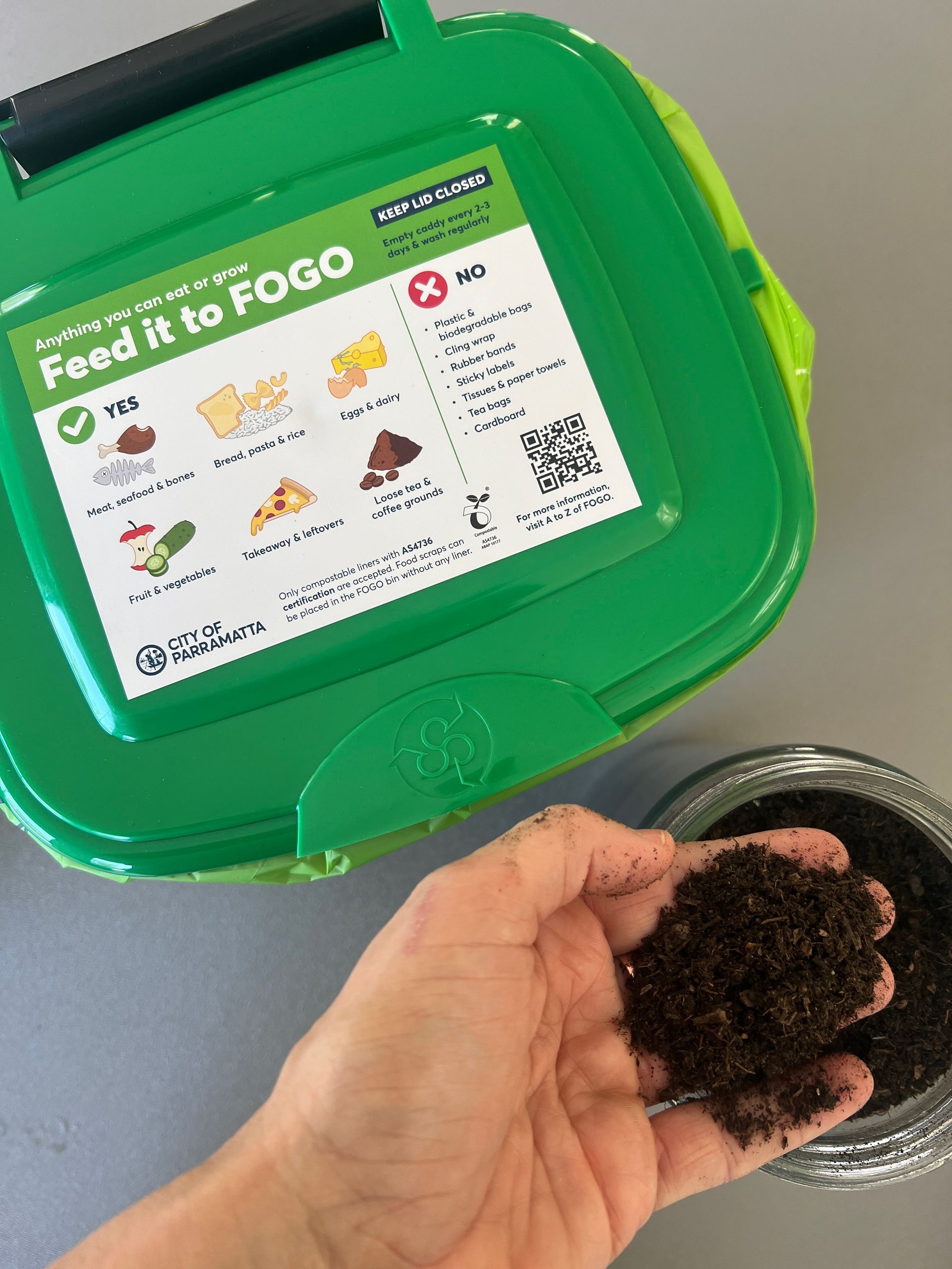A bright green FOGO bin with a labeled lid, placed at a community event hosted by Parramatta Council. The bin is designated for food and garden waste, promoting sustainable composting and waste reduction.