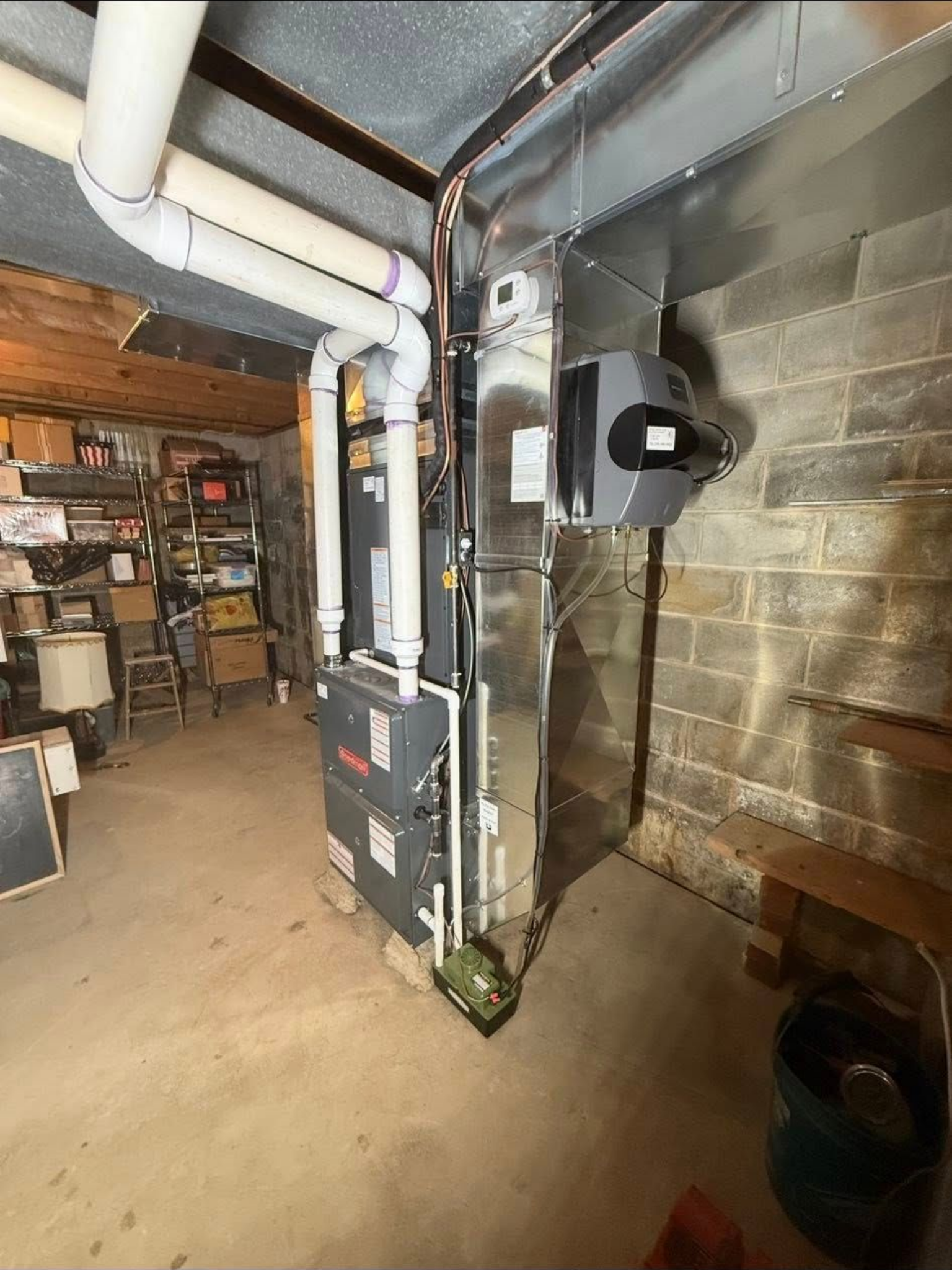 A gas furnace and attached air ventilation ductwork installed in a residential basement with a concrete block wall.