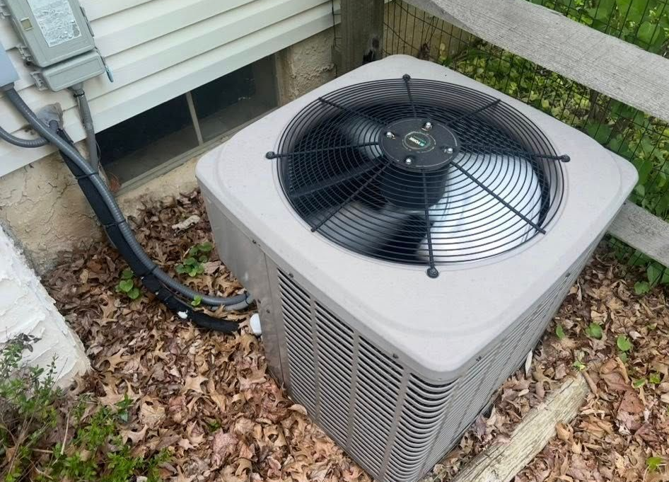 Furnace in a basement; gray metal unit, ductwork, brick walls.