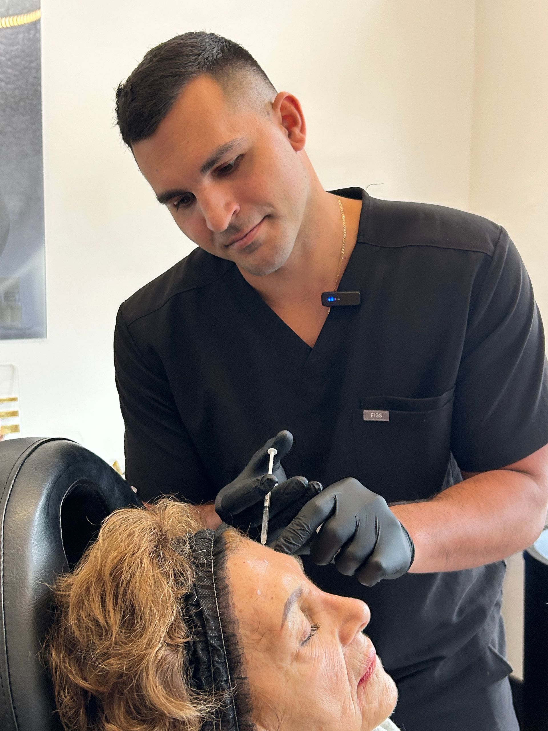 A man in scrubs giving an injection to a patient's forehead in a medical setting.