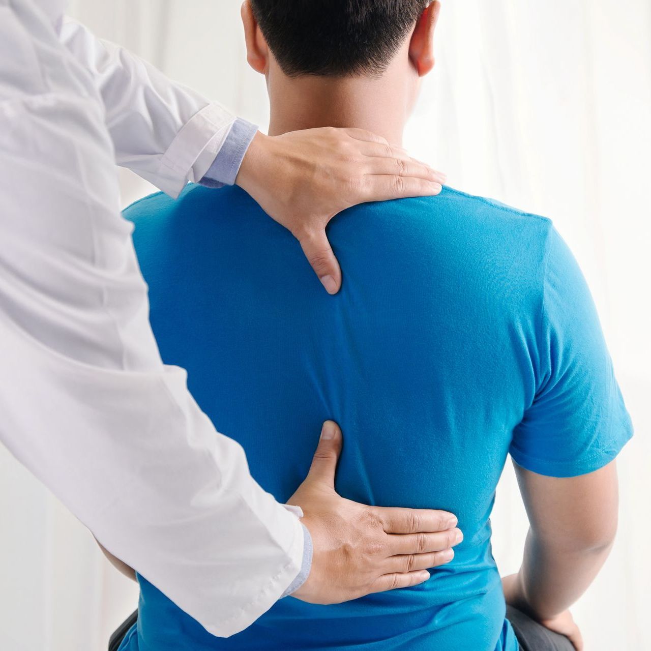 Doctor physiotherapist doing healing treatment on man's back.