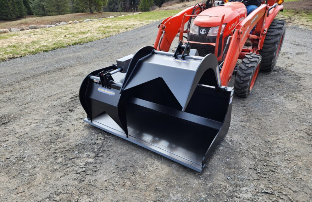 A red tractor with a black bucket is parked on the side of the road.