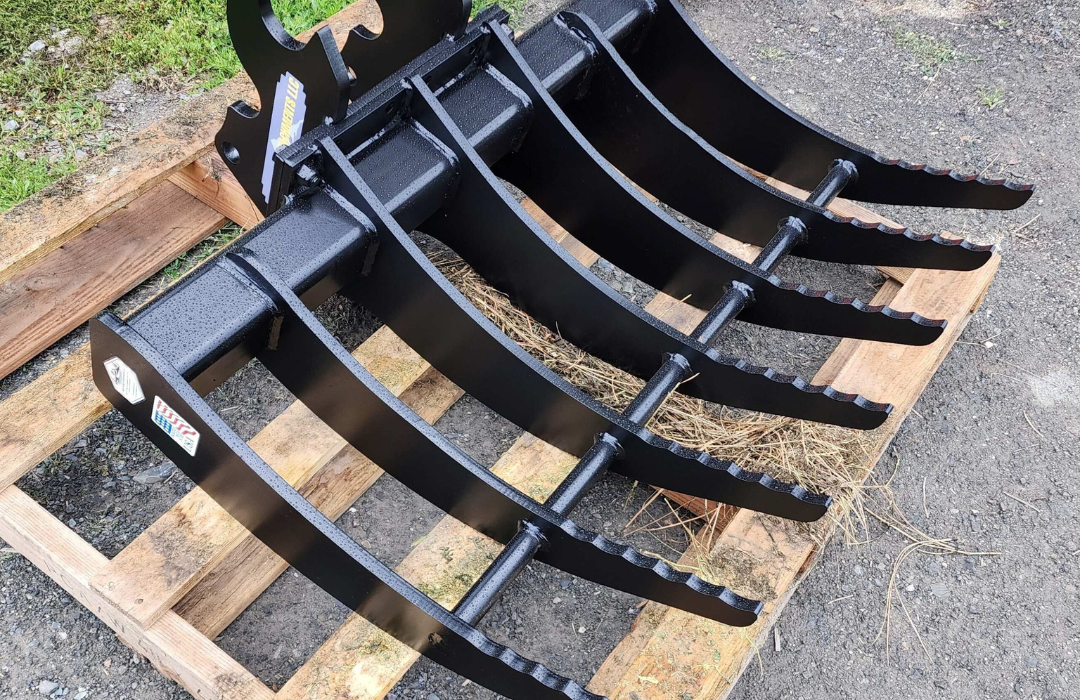 A black rake is sitting on top of a wooden pallet.