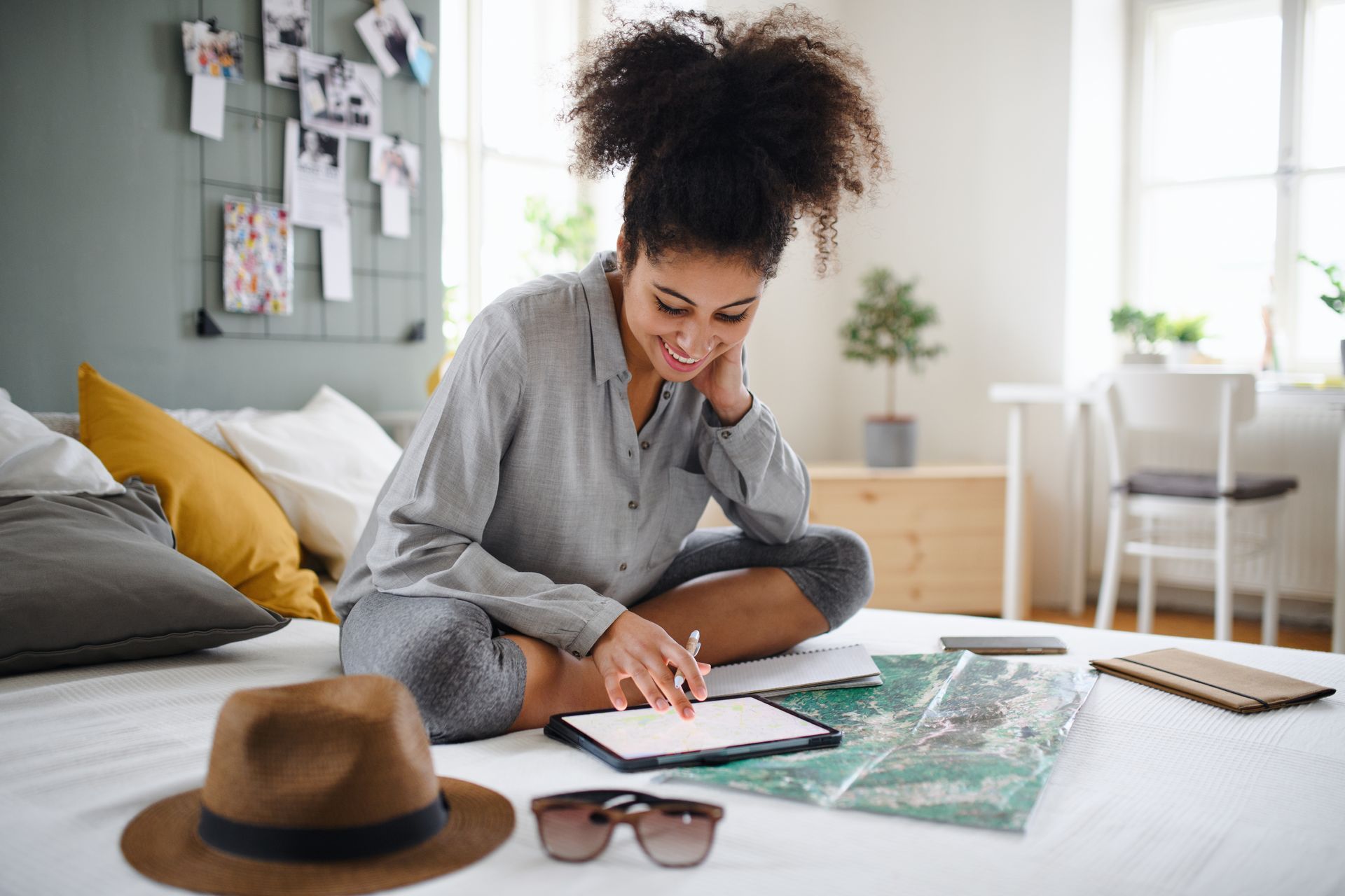 A woman is sitting on a bed using a tablet.