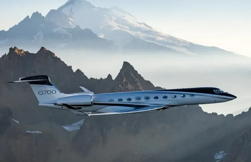A private jet is flying over a mountain range.