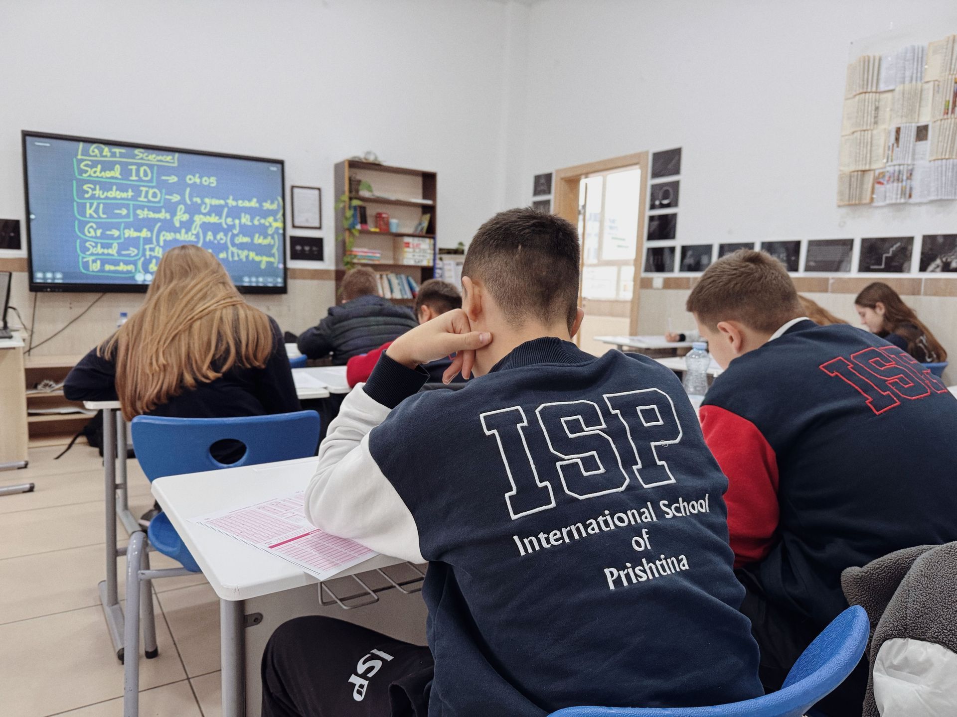 Students seated at desks facing a classroom screen during a lesson