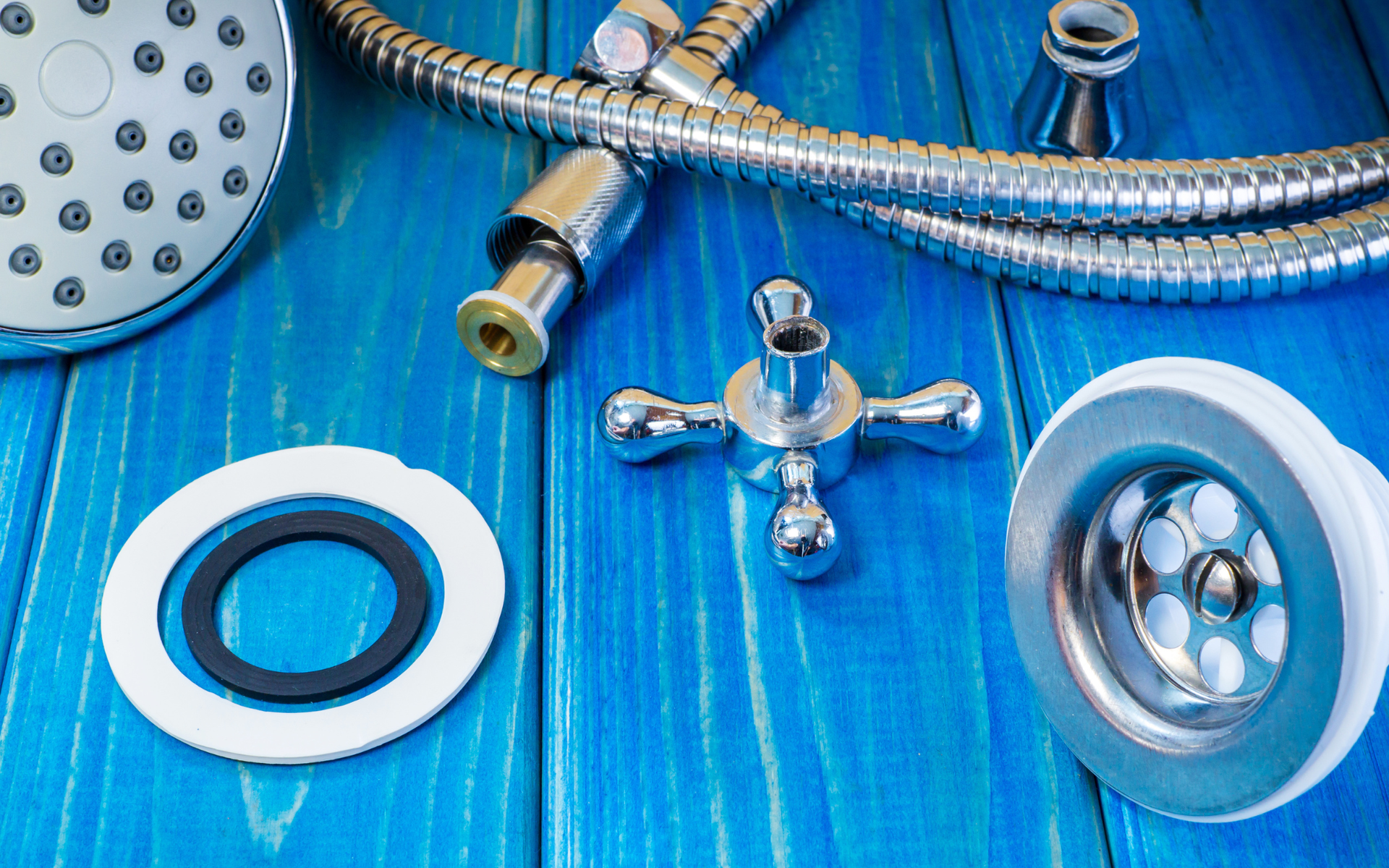 Assorted chrome shower fixtures and drains on a bright blue wooden background