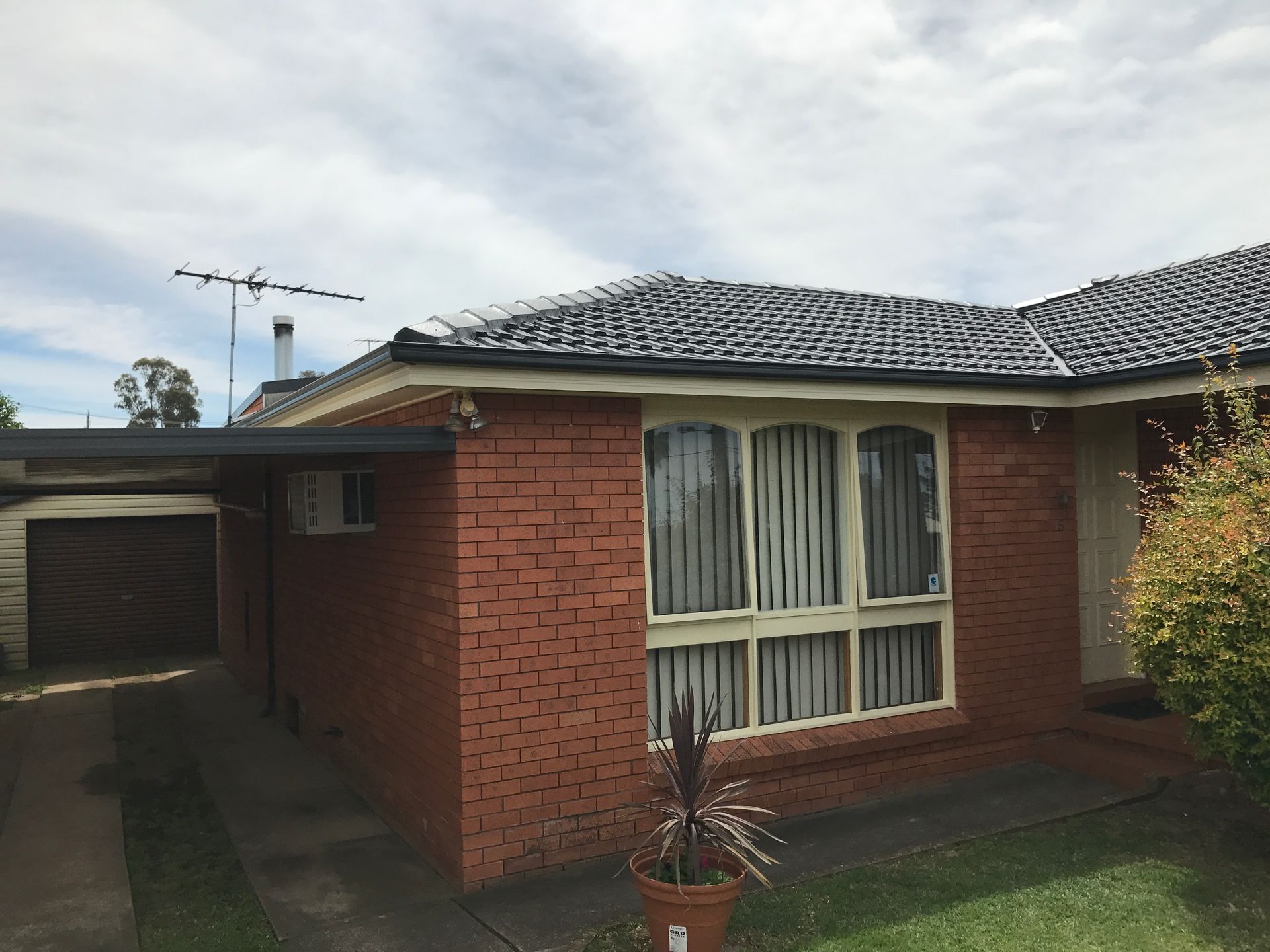 A Person Wearing Yellow Gloves is Working on a Roof — Norwest Roof Restorations In Blue Bay, NSW