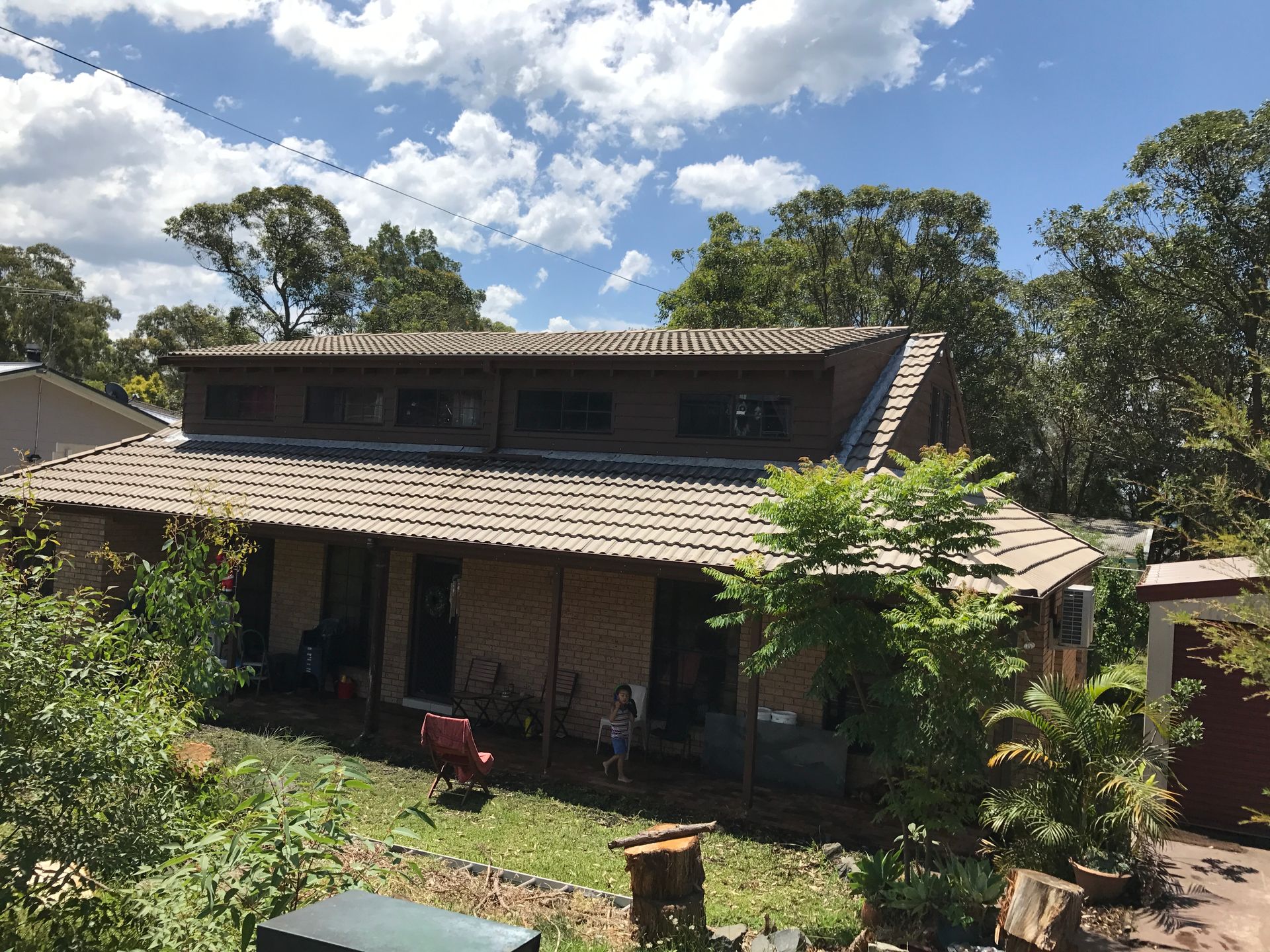 A Man Wearing a Helmet Uses a Power Drill on a Wooden Roof — Norwest Roof Restorations In Blue Bay, NSW