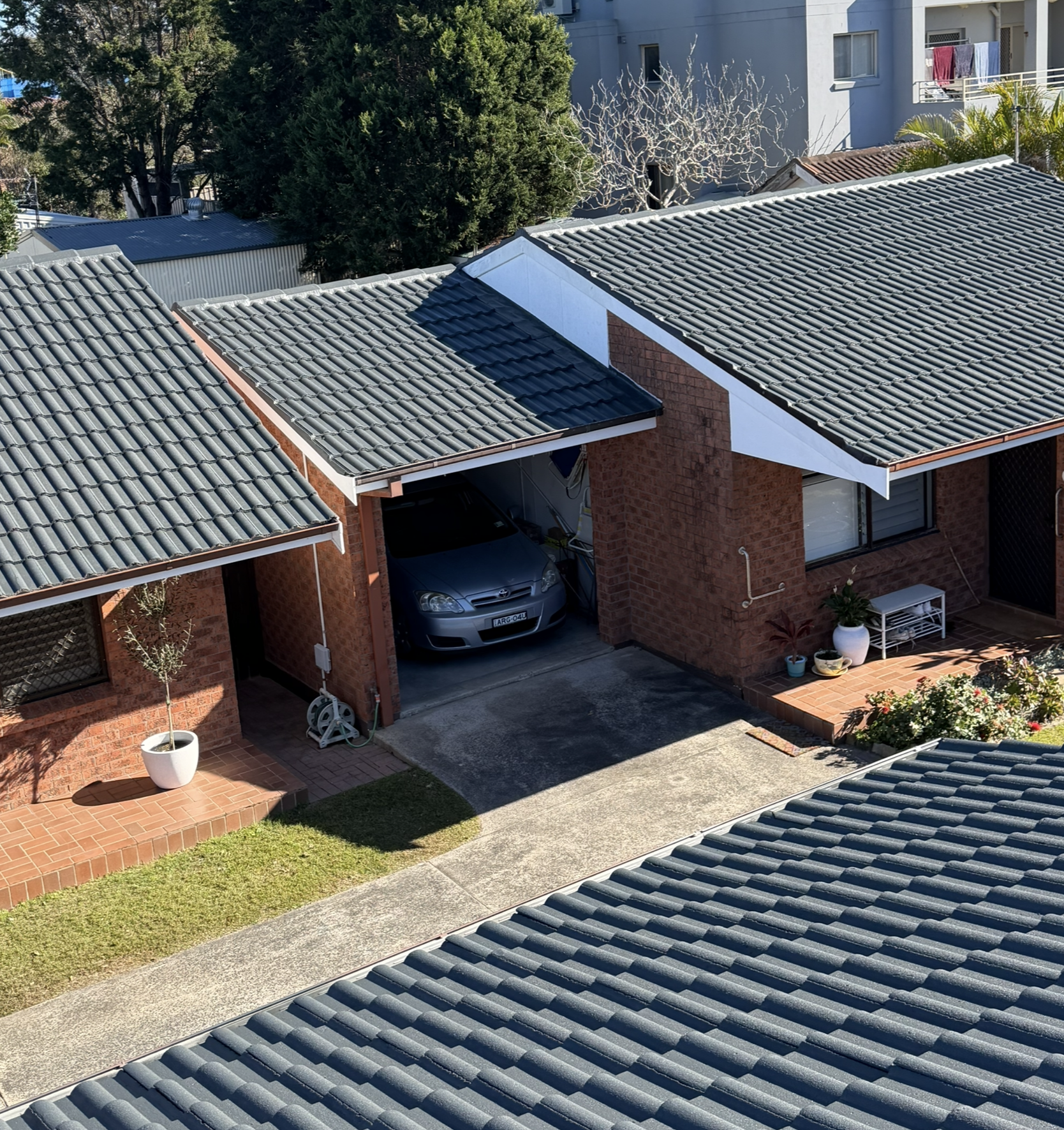 A Metal Roof With Overlapping Brown Tiles — Norwest Roof Restorations In Blue Bay, NSW
